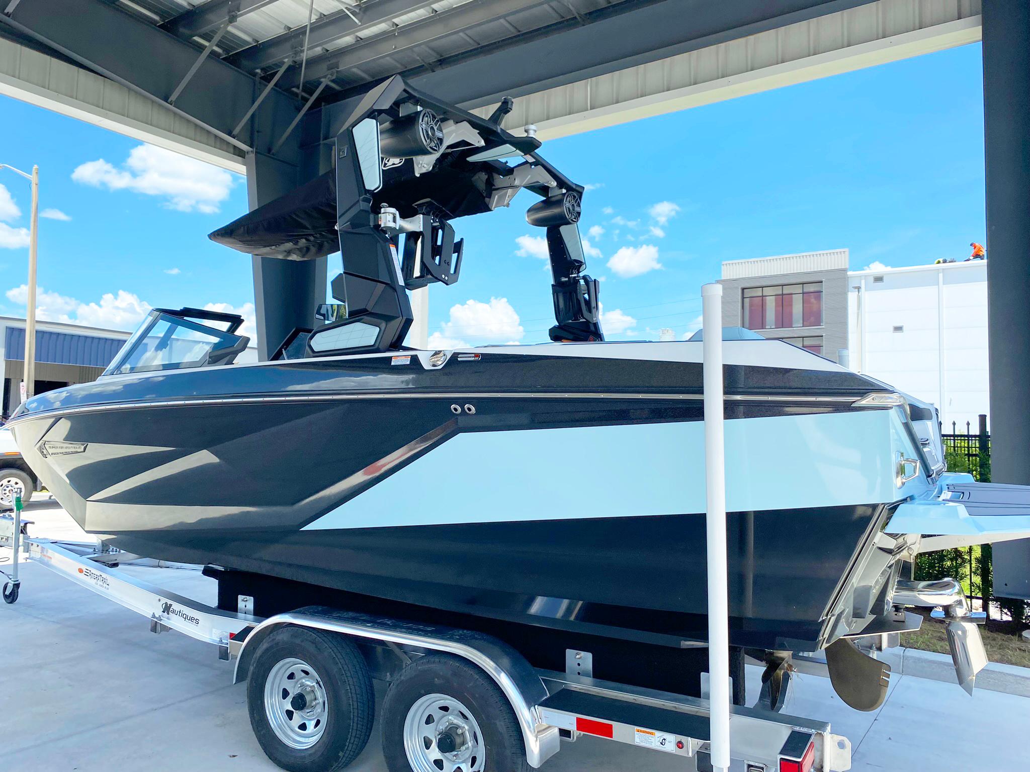 2024 Nautique Super Air Nautique G21 boat on trailer under a metal roof.