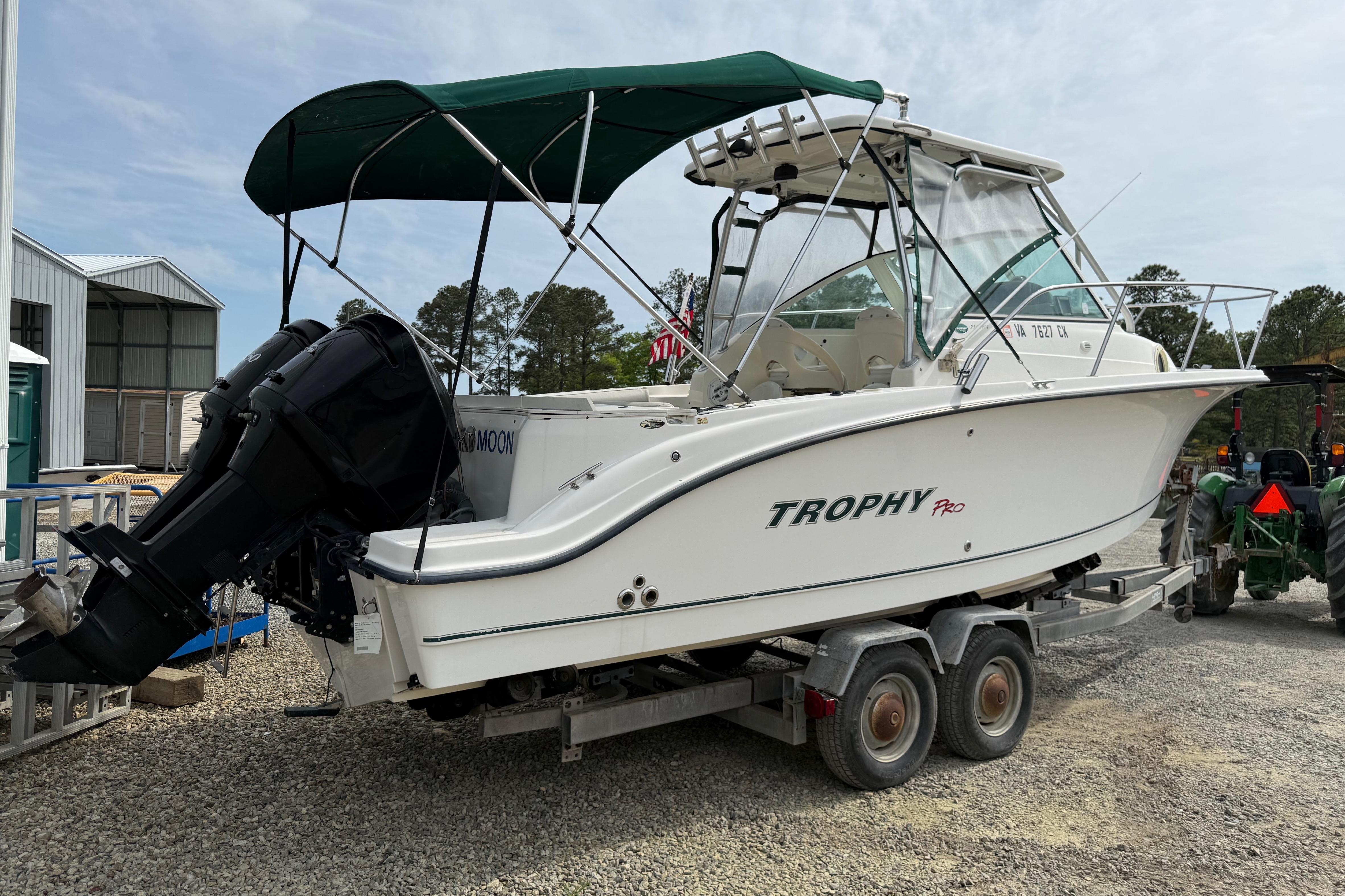 2006 Trophy 2502 Walkaround boat on trailer with green canopy and outboard motor.