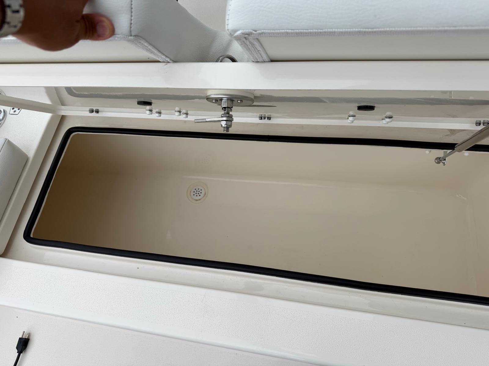An open storage compartment on a boat with white upholstery.