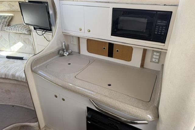 Interior of 1999 Sea Ray 290 Sundancer with kitchenette, featuring sink and microwave.