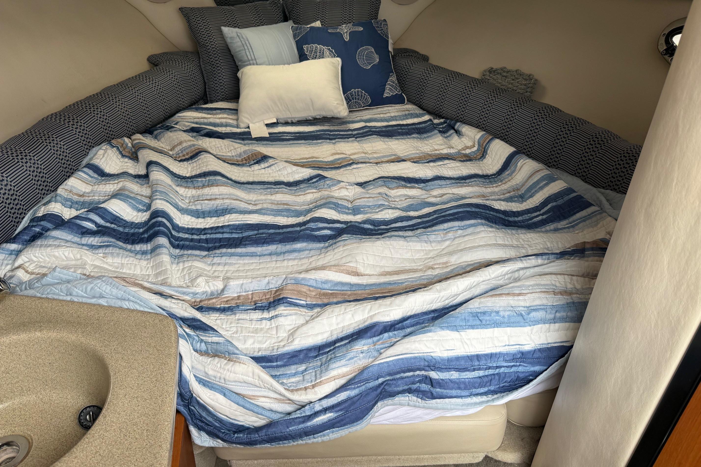 Cozy cabin interior of 2005 Crownline 250 CR with striped bedding and pillows.