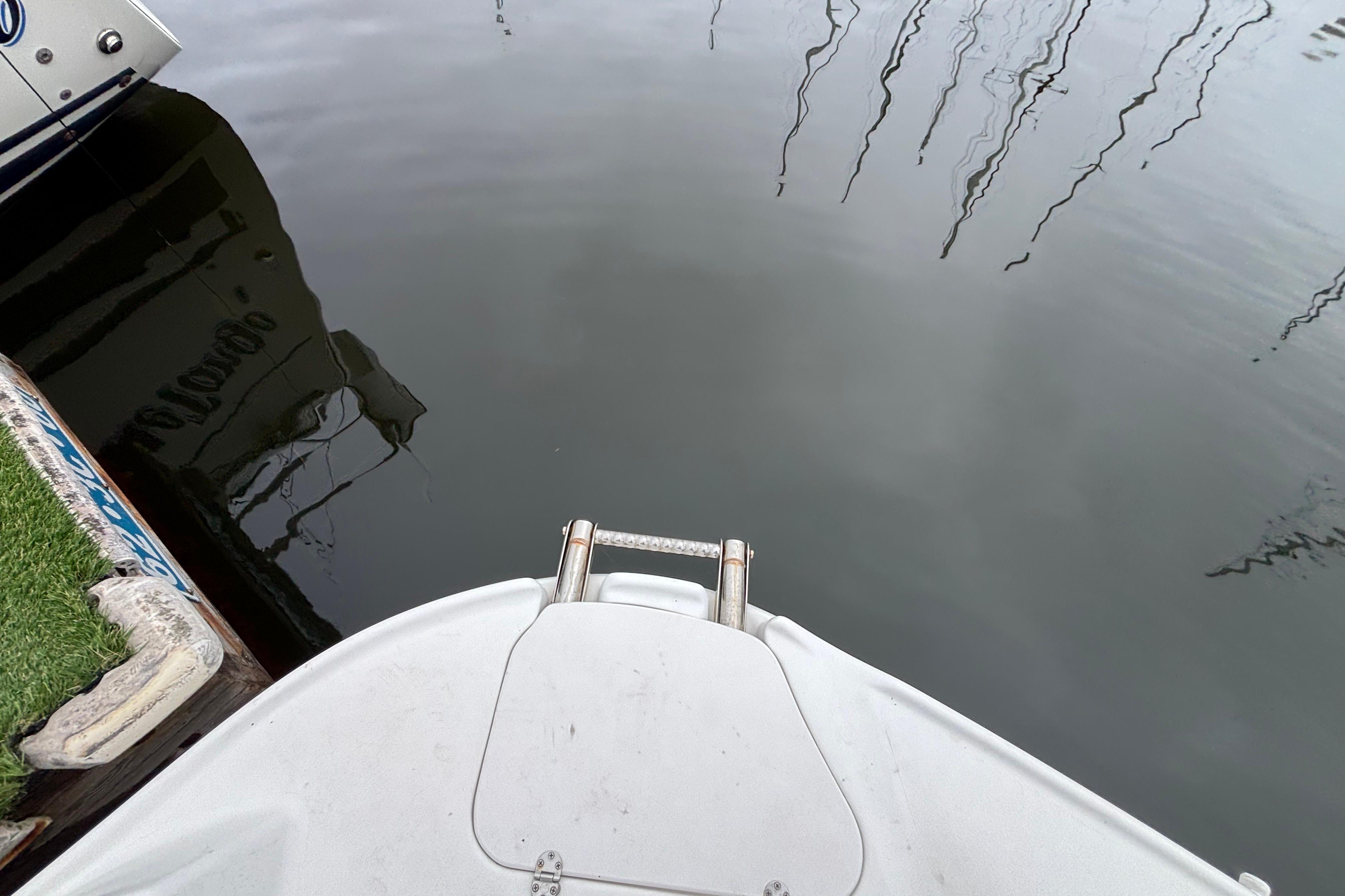 Bow of a 2004 Larson 310 boat docked on calm water.