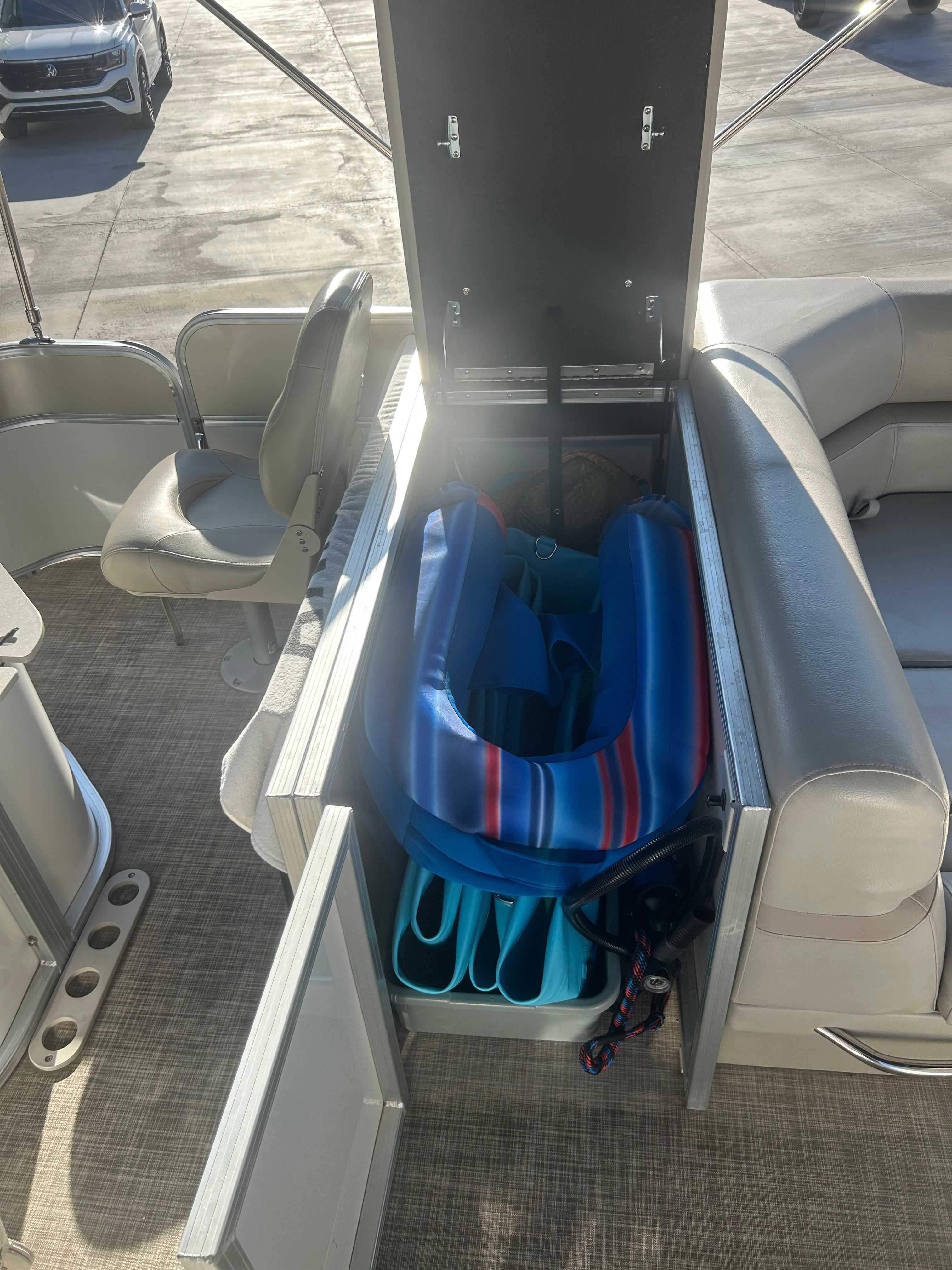 An open storage compartment on a boat with blue life vests and accessories.