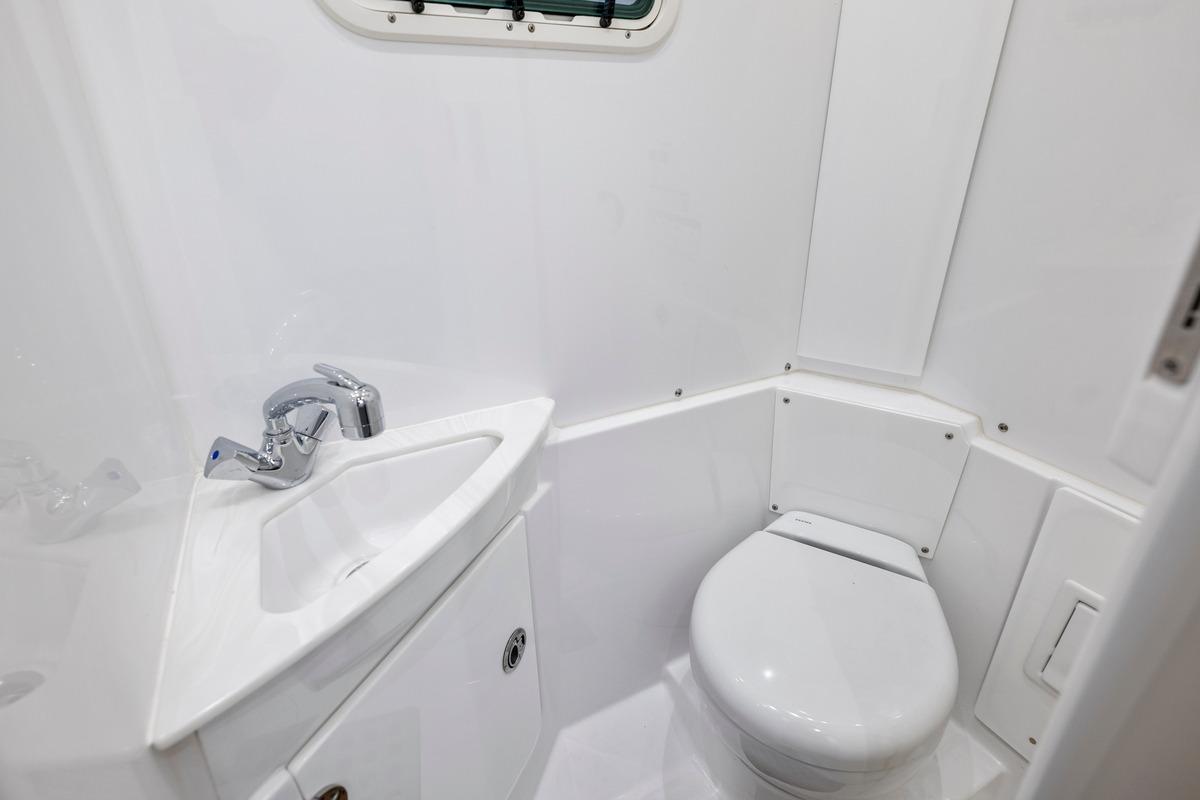 Compact bathroom in 2026 Everglades 375 Center Console boat, featuring sink and toilet.
