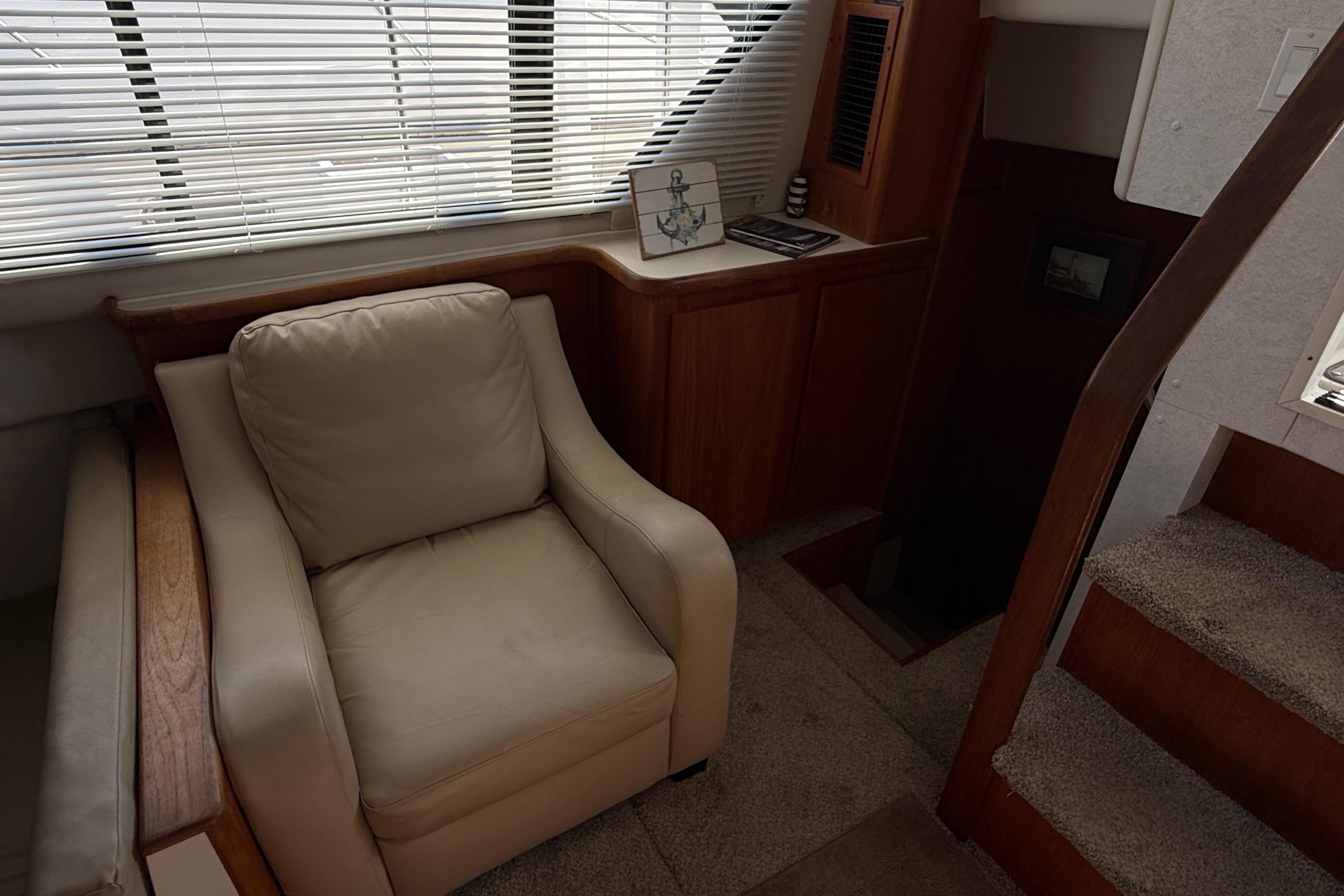 Interior of 1992 Carver 33 Aft Cabin Motor Yacht with beige armchair and wooden accents.