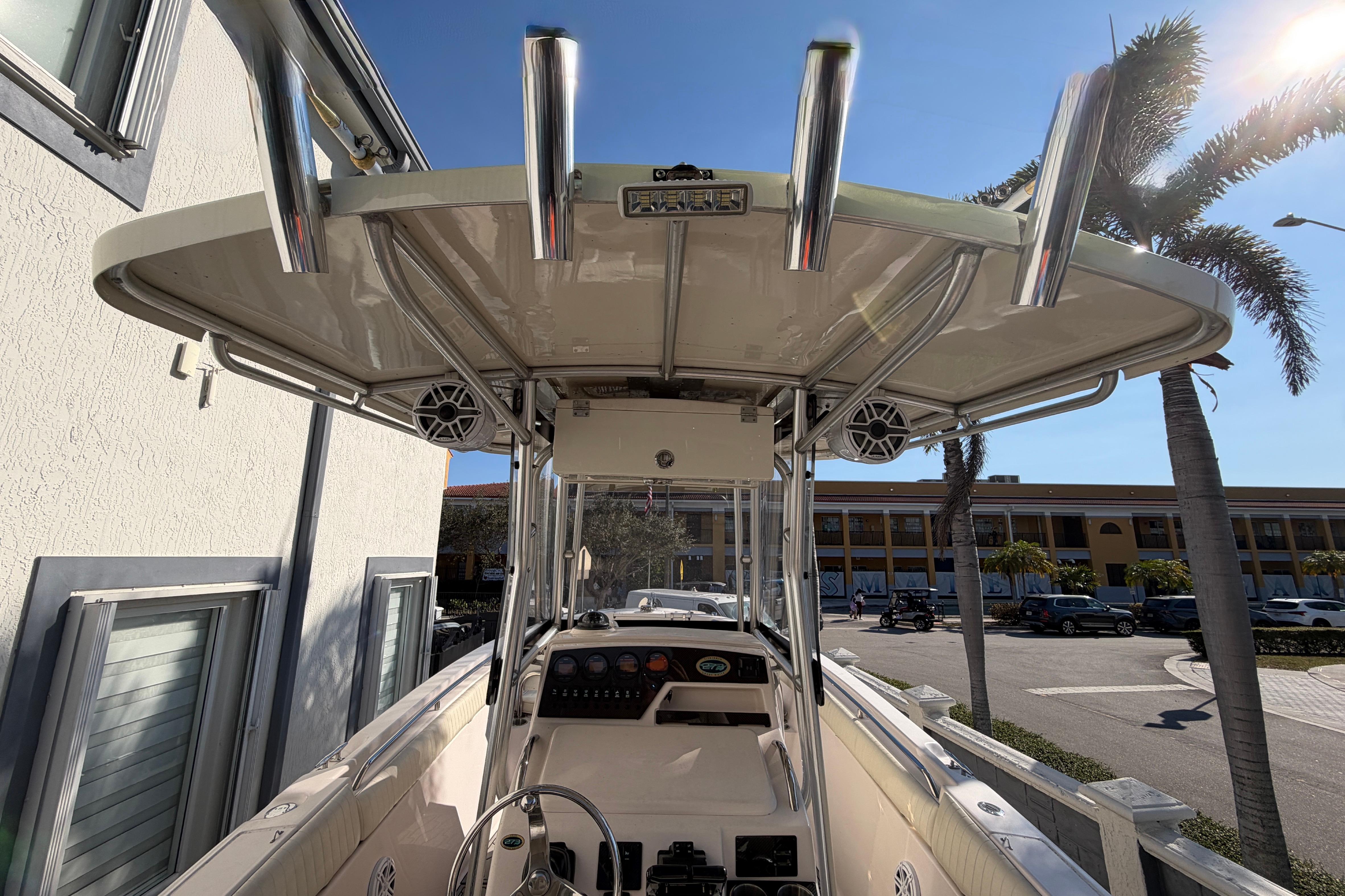 2004 Grady White 273 boat with T-top and rod holders, parked near palm trees.