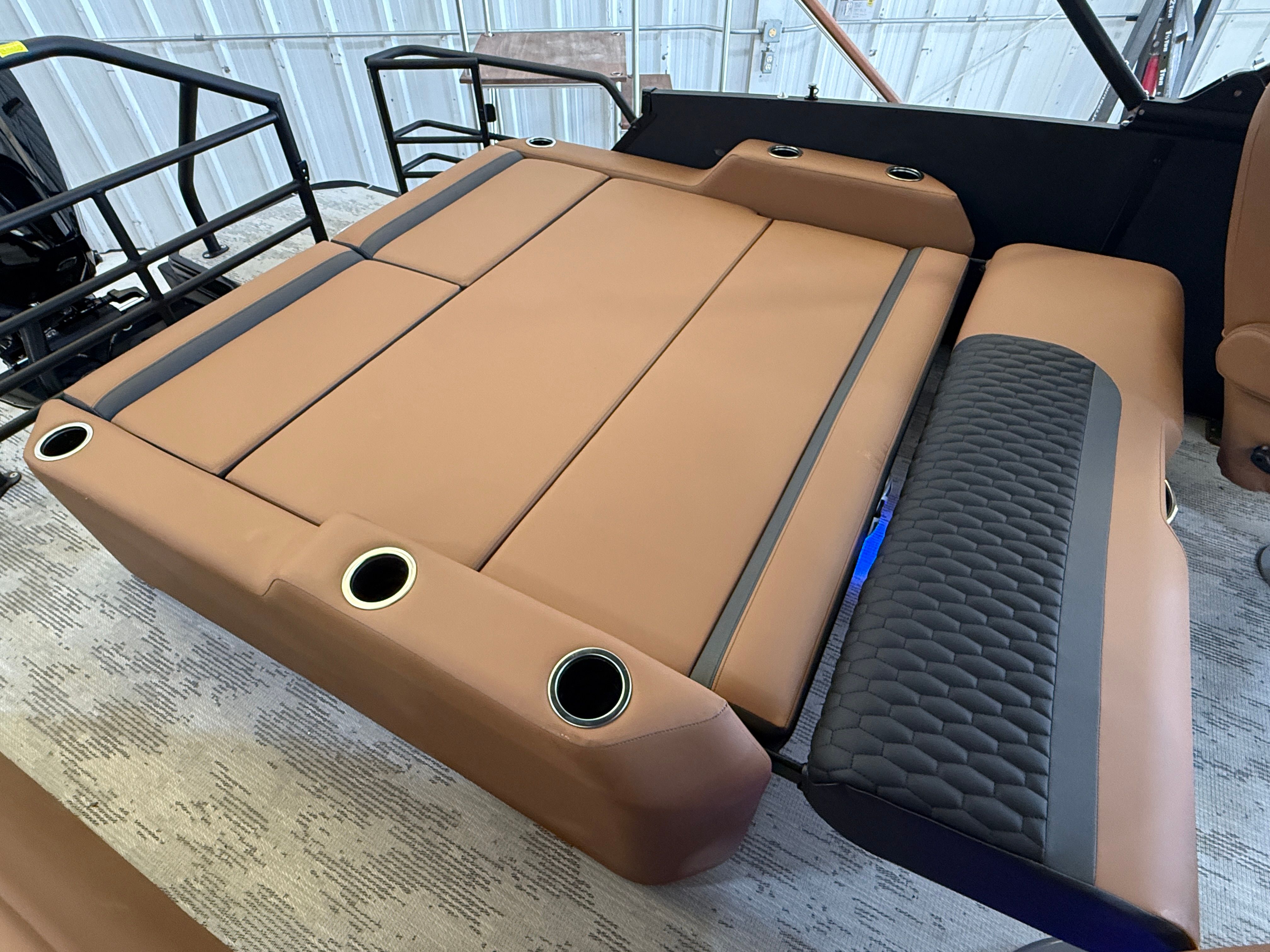 The image shows a luxurious lounge area with brown upholstery and cup holders on a boat.