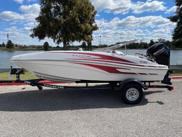 2024 Tahoe T16 boat on trailer by a lake under a blue sky.