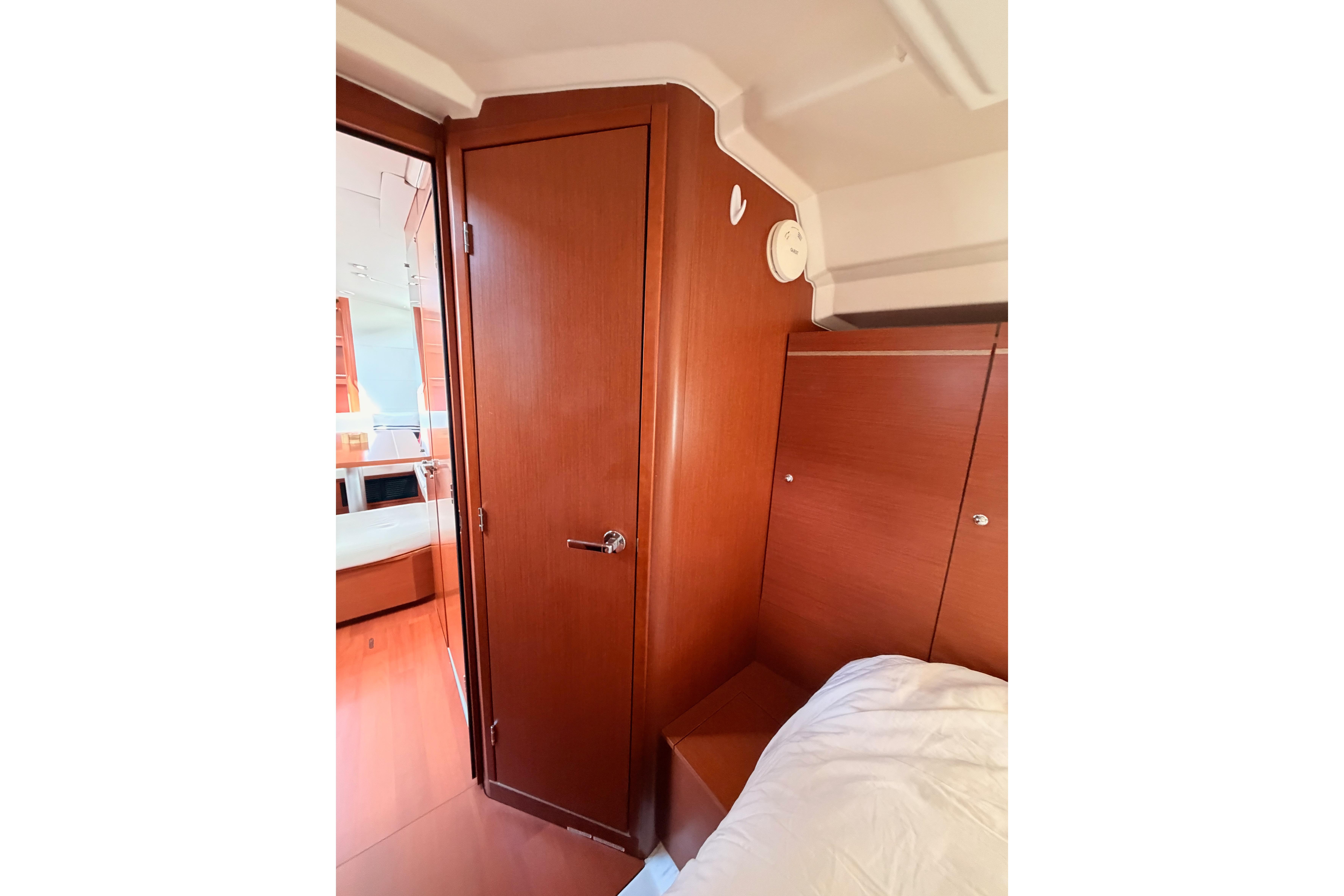 Interior cabin of 2020 Beneteau Oceanis 46.1 yacht, featuring wooden door and cozy bed.