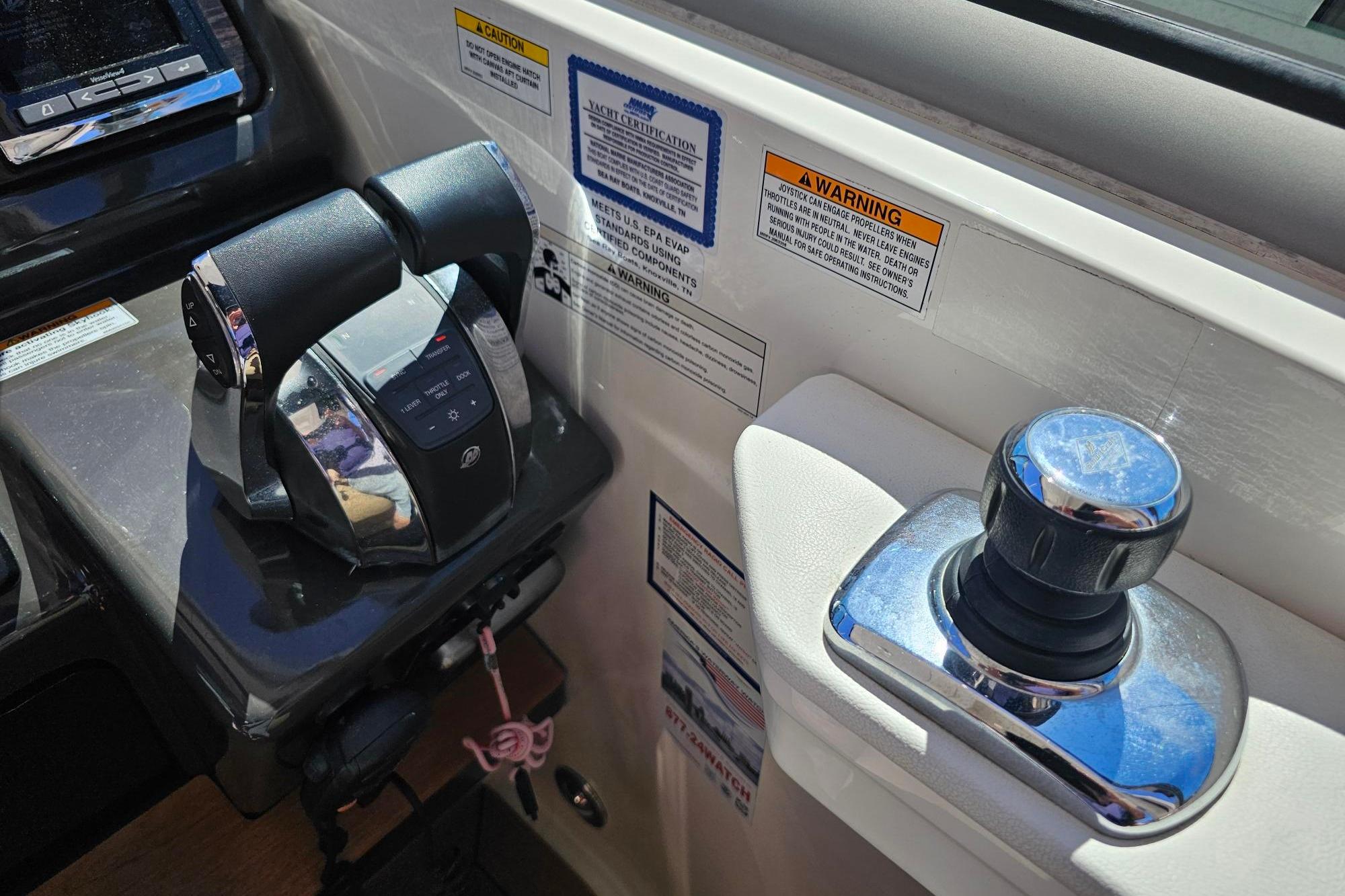 2016 Sea Ray Sundancer 350 helm controls with throttle and joystick, featuring warning labels.