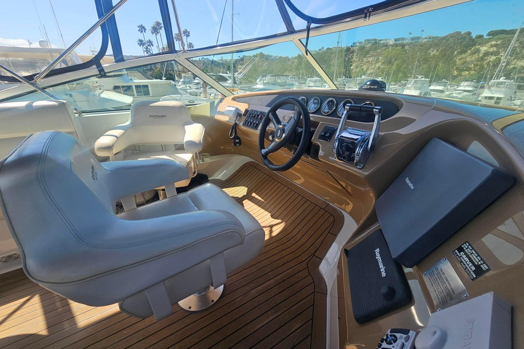 Pilothouse interior of 2002 Carver 450 Voyager, featuring helm and seating with marina view.
