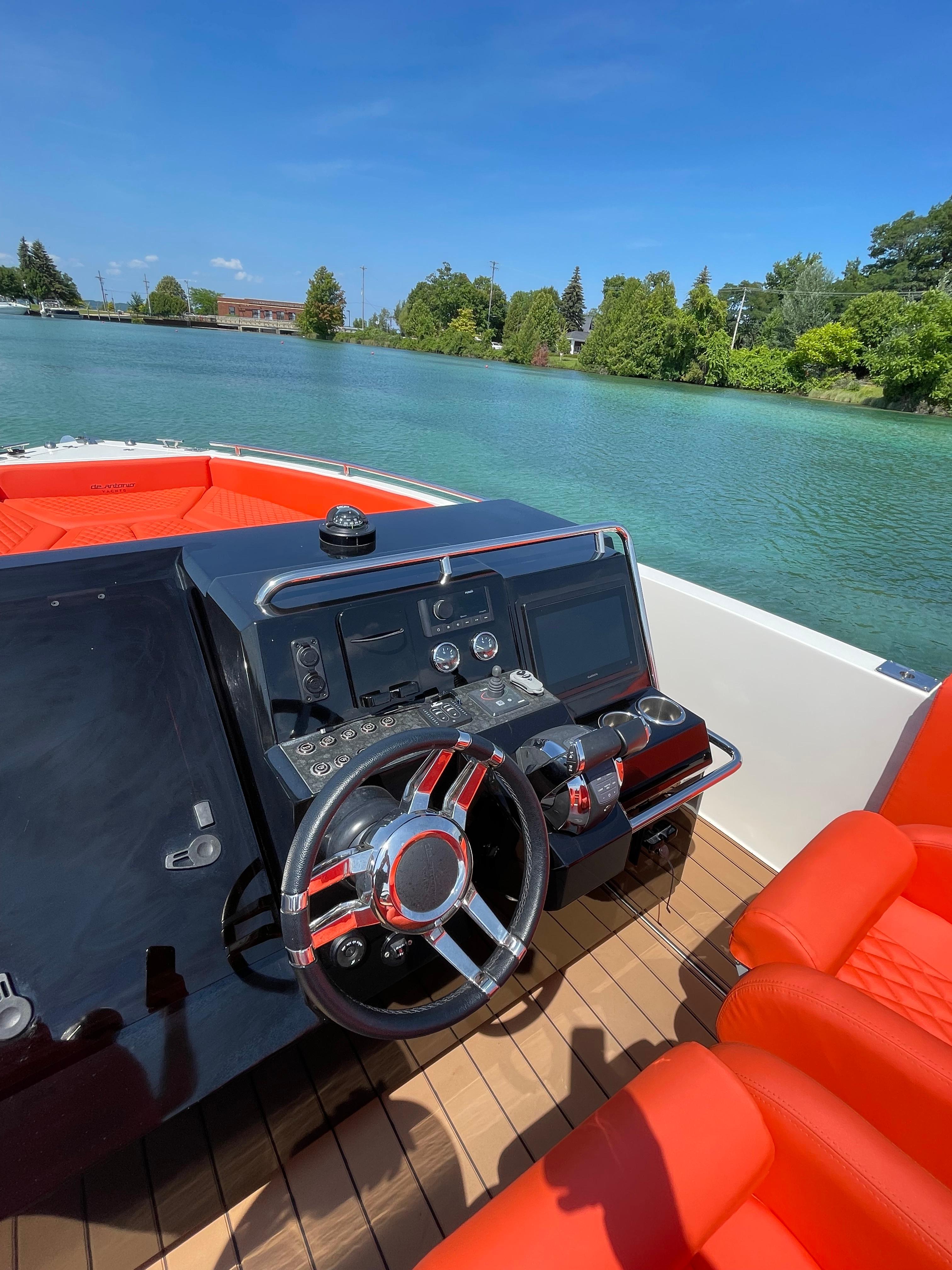 2020 De Antonio Yachts D 28 helm with red seating on a serene lake.