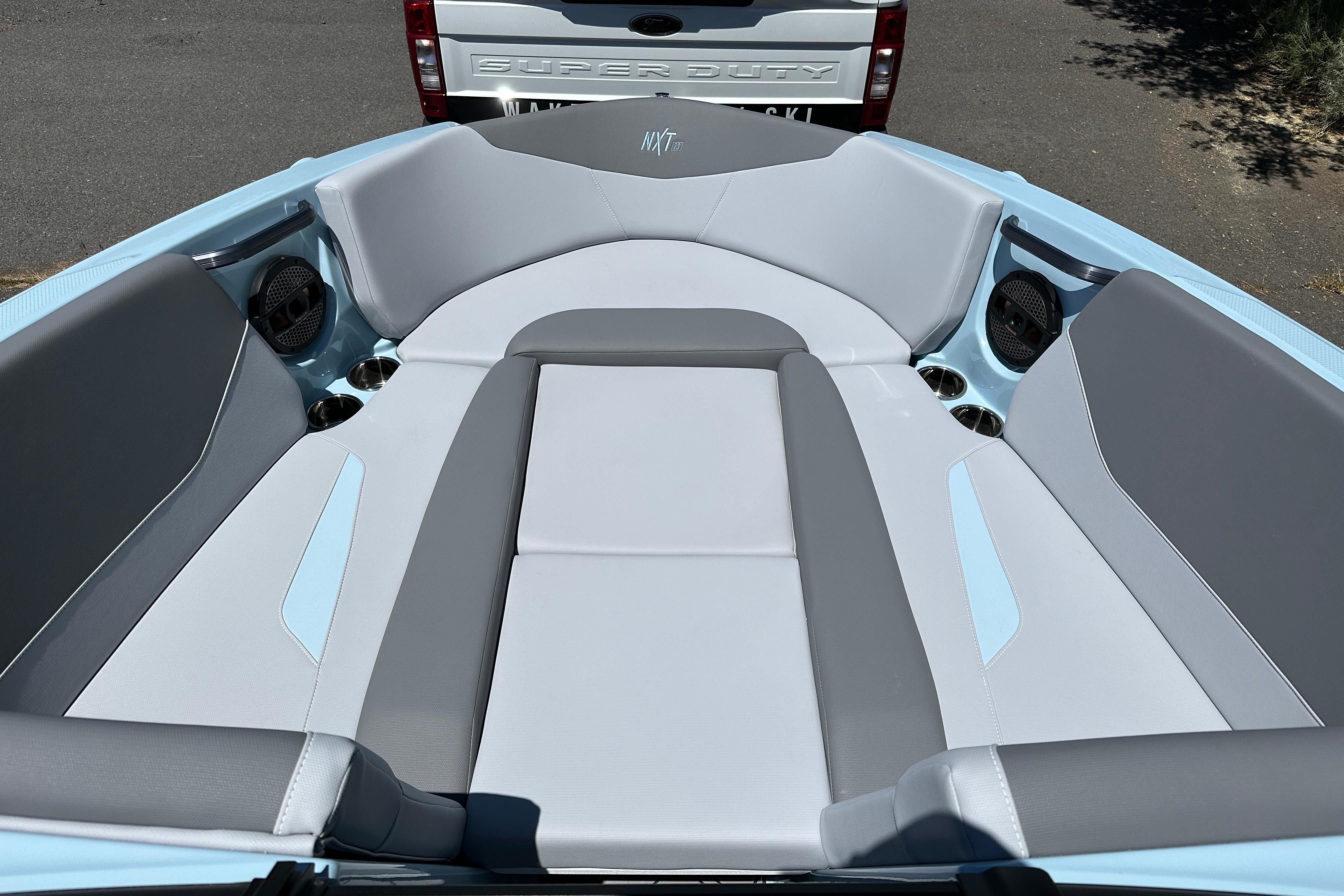 2023 MasterCraft NXT23 boat interior with gray and blue seating, featuring cup holders and speakers.