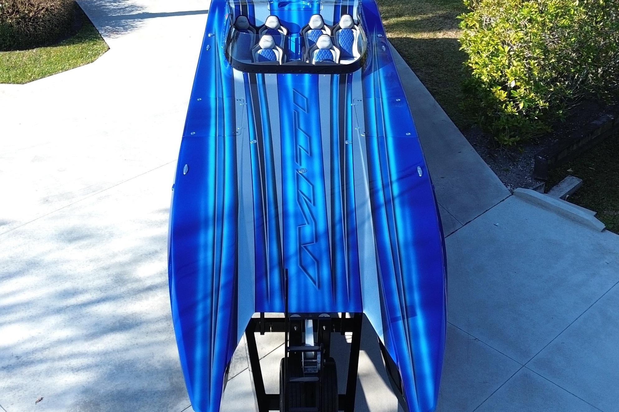 Blue 2016 MTI 44 RP speedboat with sleek design, parked on concrete driveway.