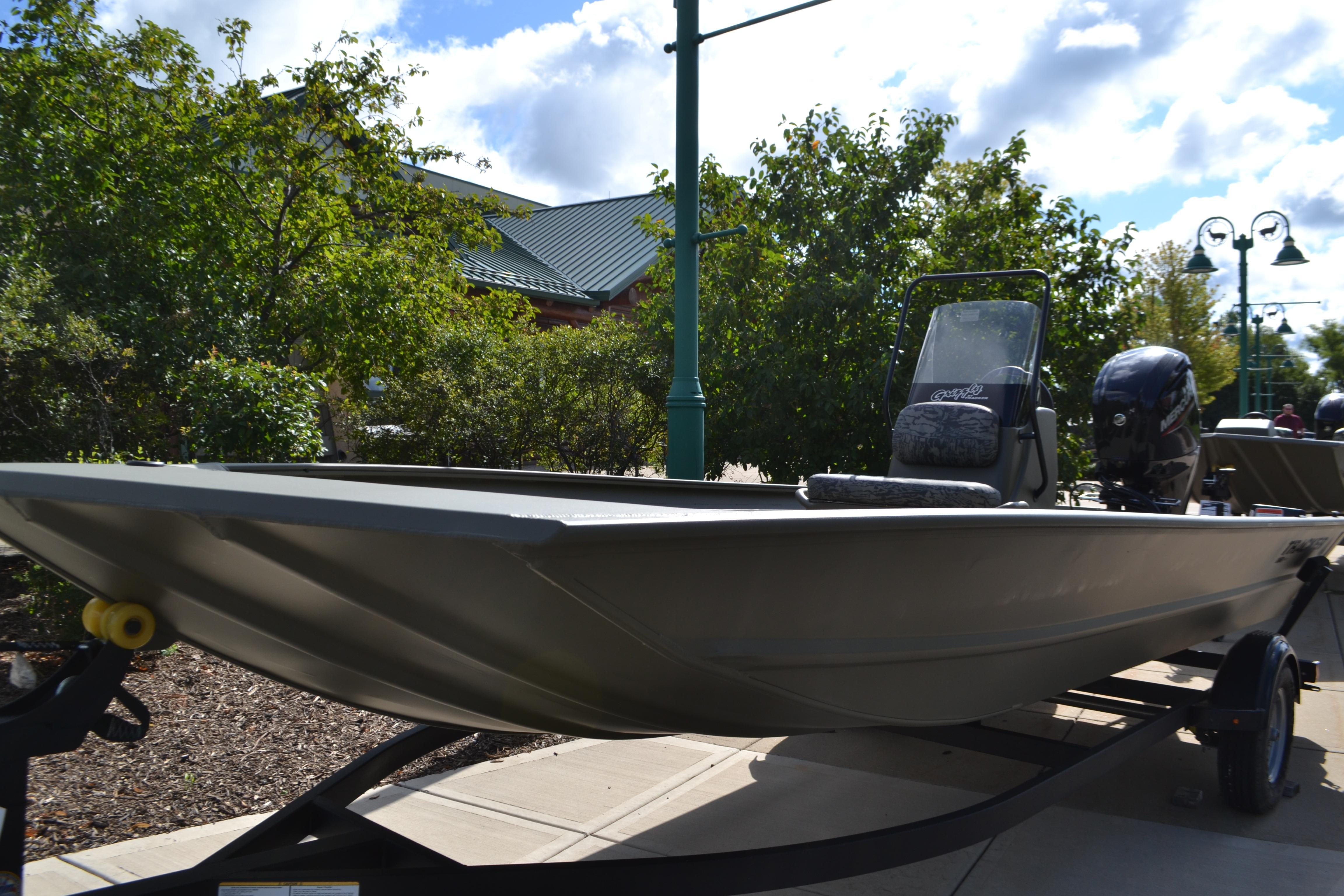 2026 Tracker Grizzly 1860 CC boat on trailer, outdoors with trees and sky background.