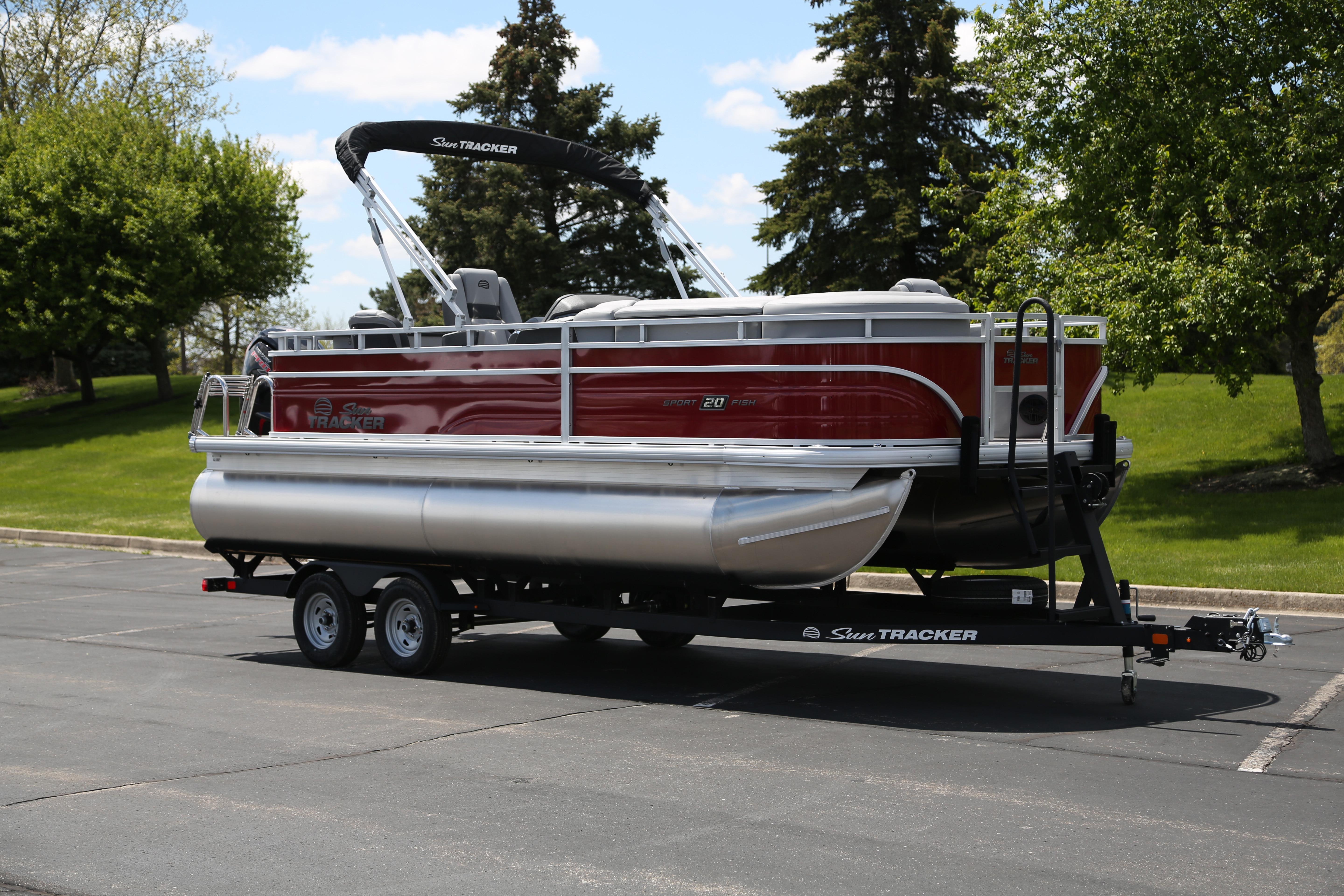 2026 Sun Tracker SportFish 20 DLX pontoon boat on trailer in a parking lot.
