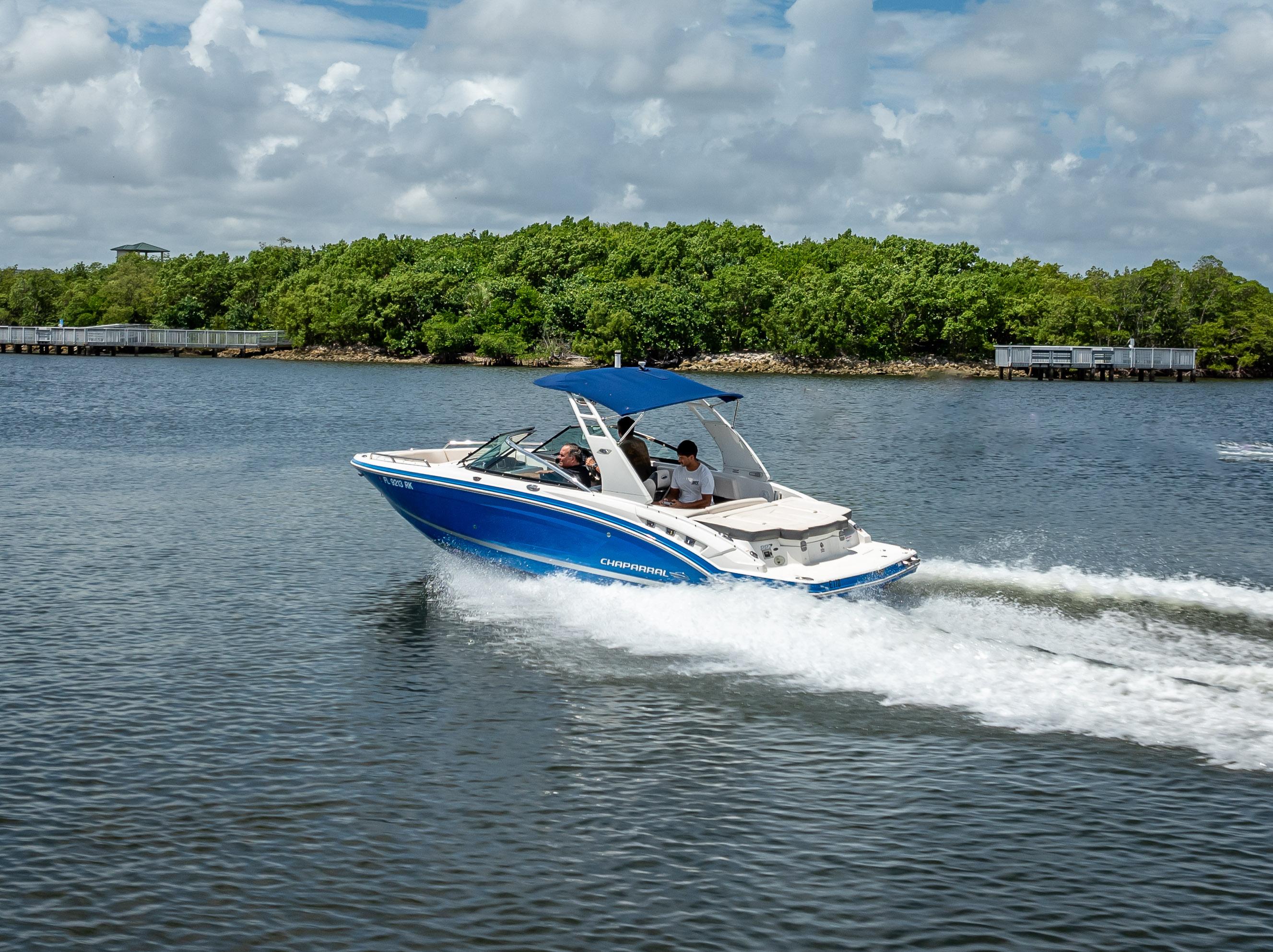 2017 Chaparral 227 SSX boat cruising on a scenic lake with lush greenery.
