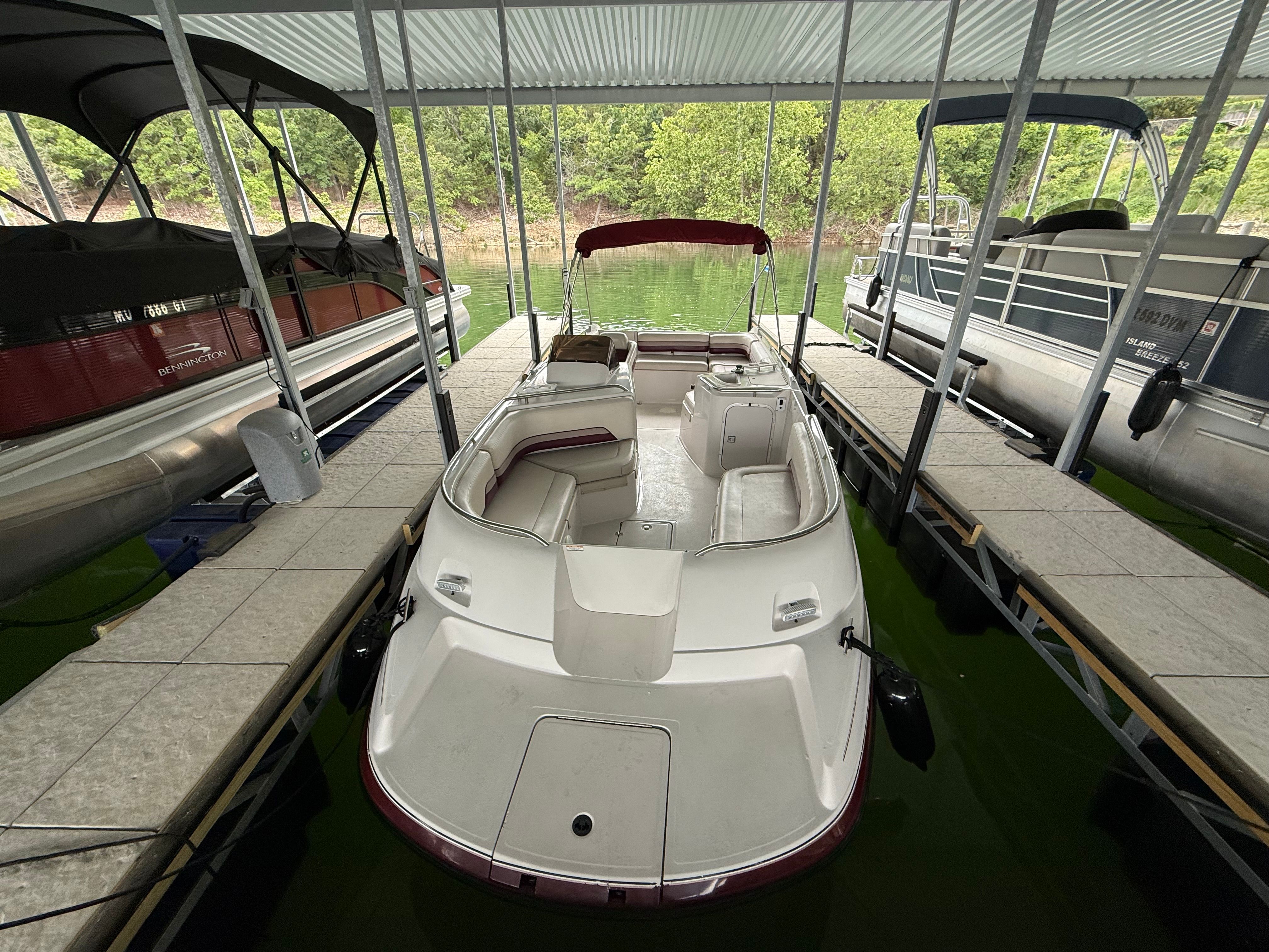 A 1994 Chaparral Sunesta 220 is docked under a covered area. It features white and red upholstery.