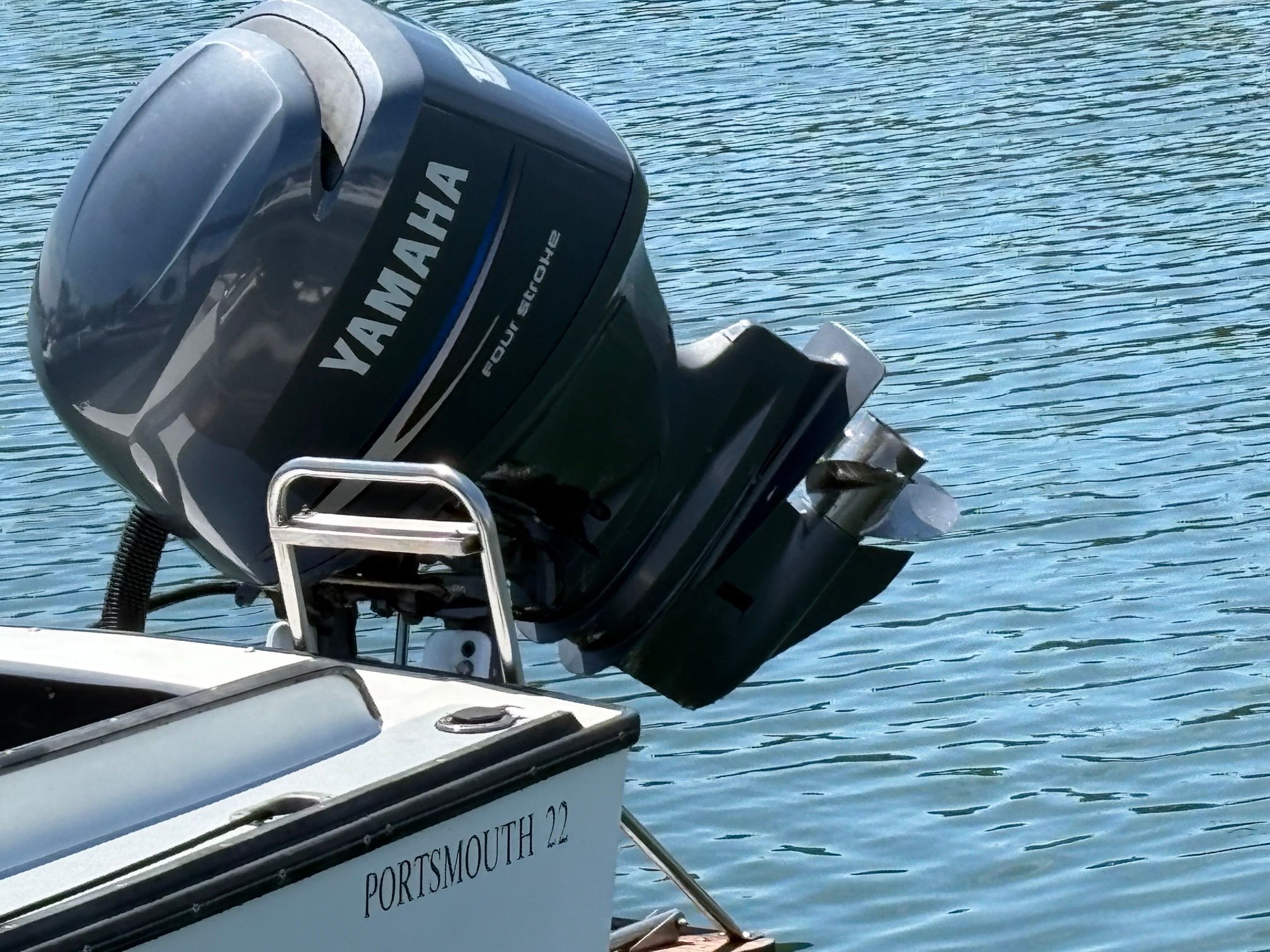 Outboard motor of a Portsmouth 22 boat on calm water.