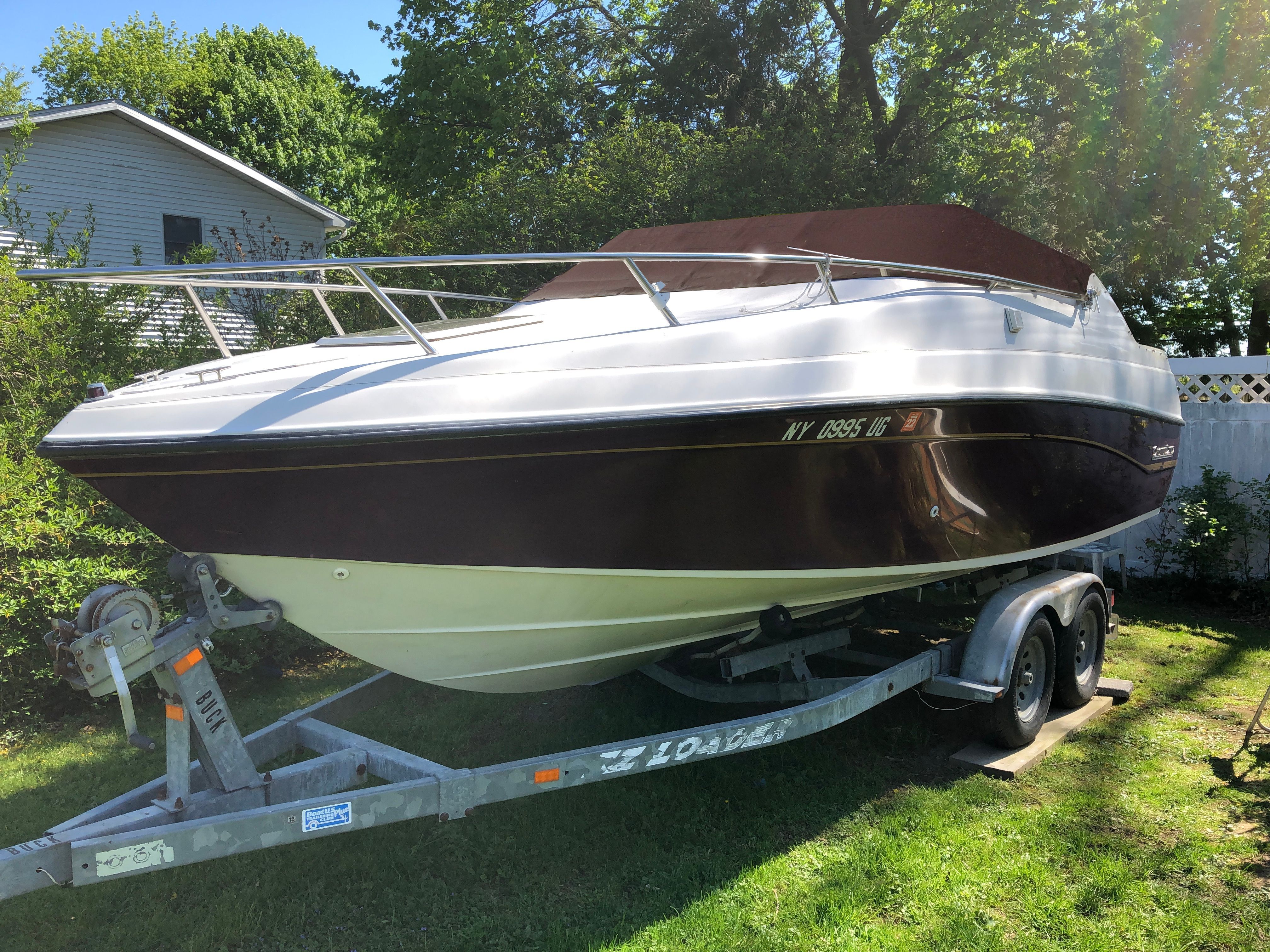 A 1992 Crownline Cudy Cruser on a trailer in a garden setting.