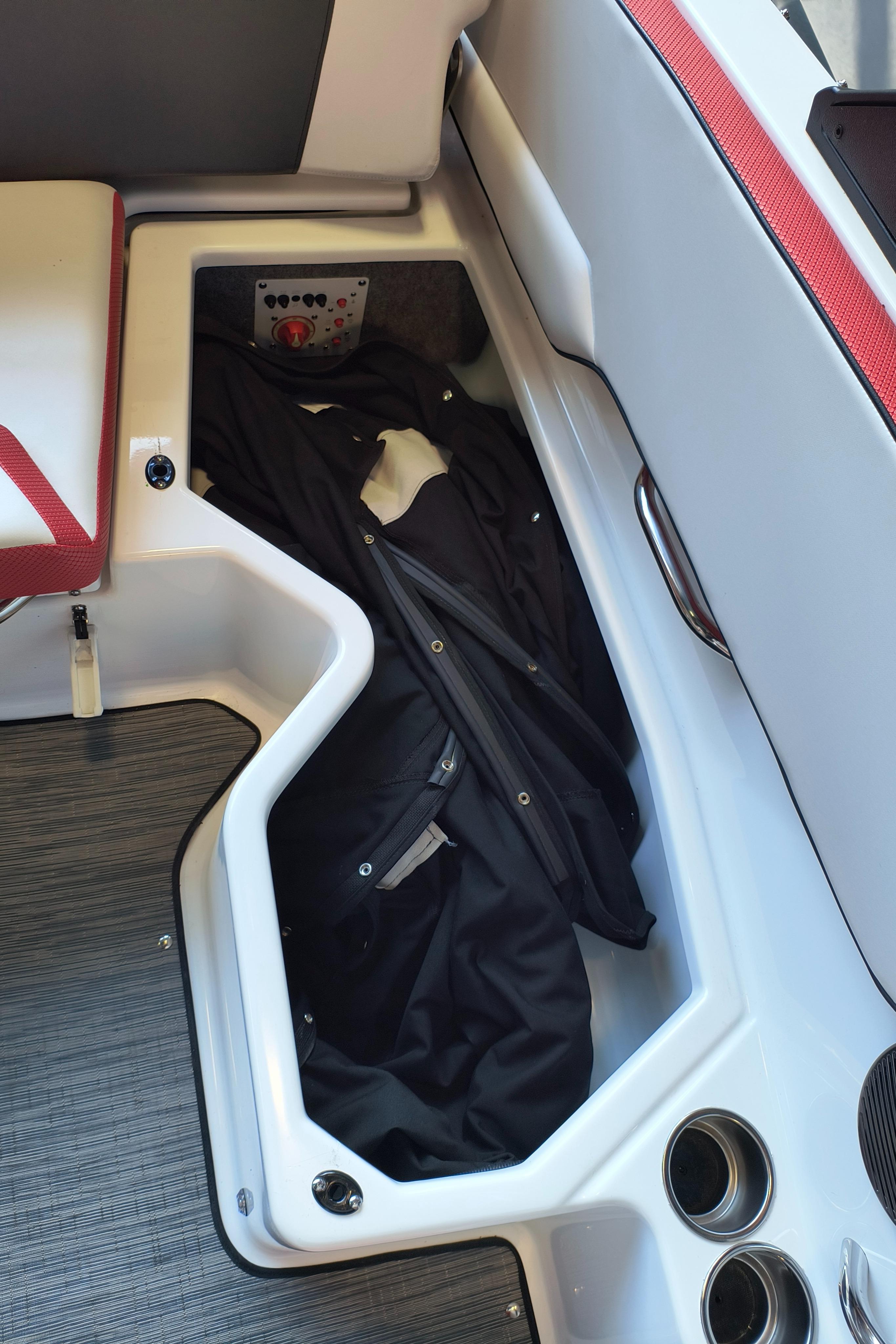 Storage compartment in 2023 Scarab 195 ID boat with black jacket inside.