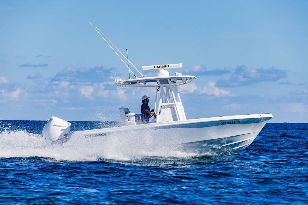 2024 Reef Runner 230 Open boat cruising on open water under clear blue skies.