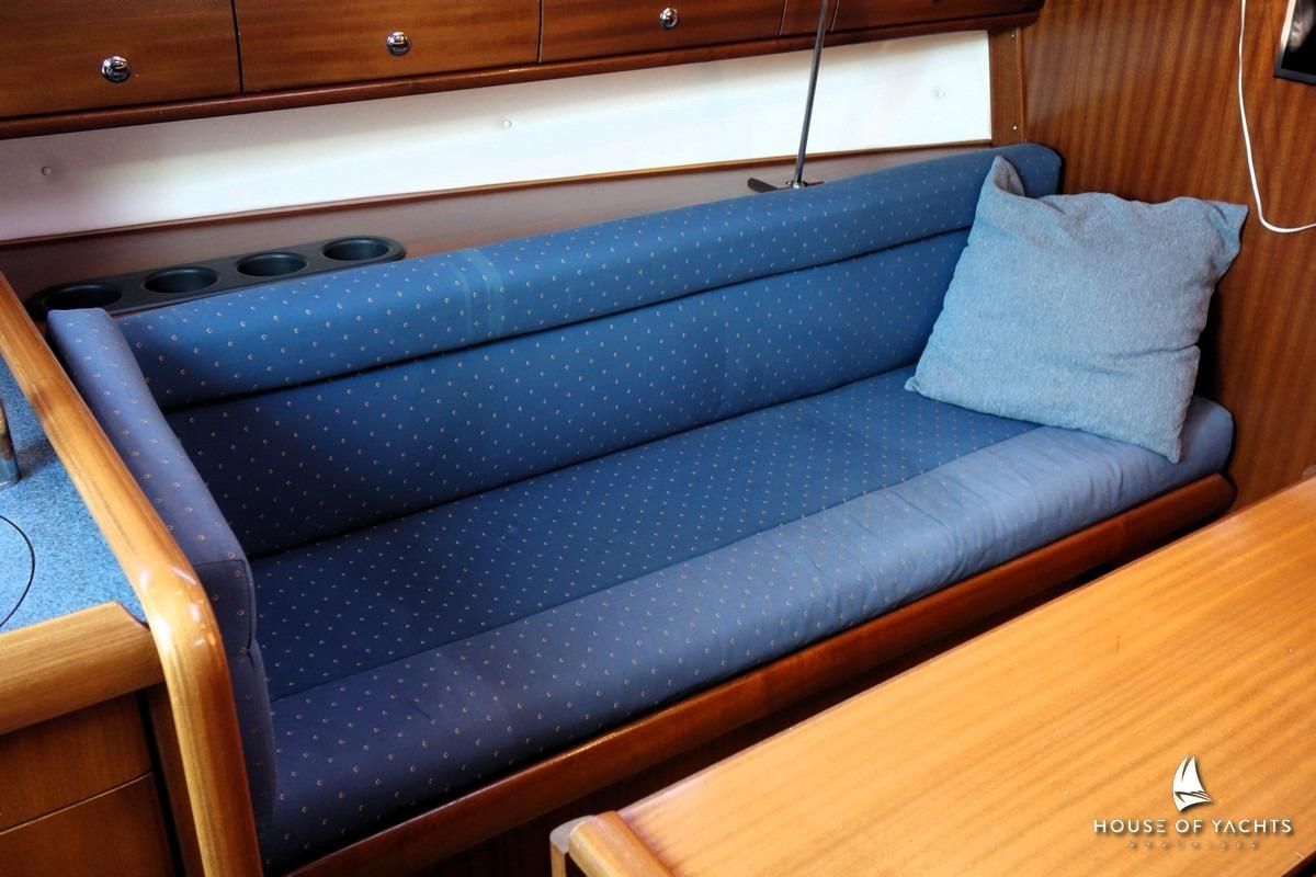 Blue cushioned seating area inside a 2003 Bavaria 32 yacht cabin.