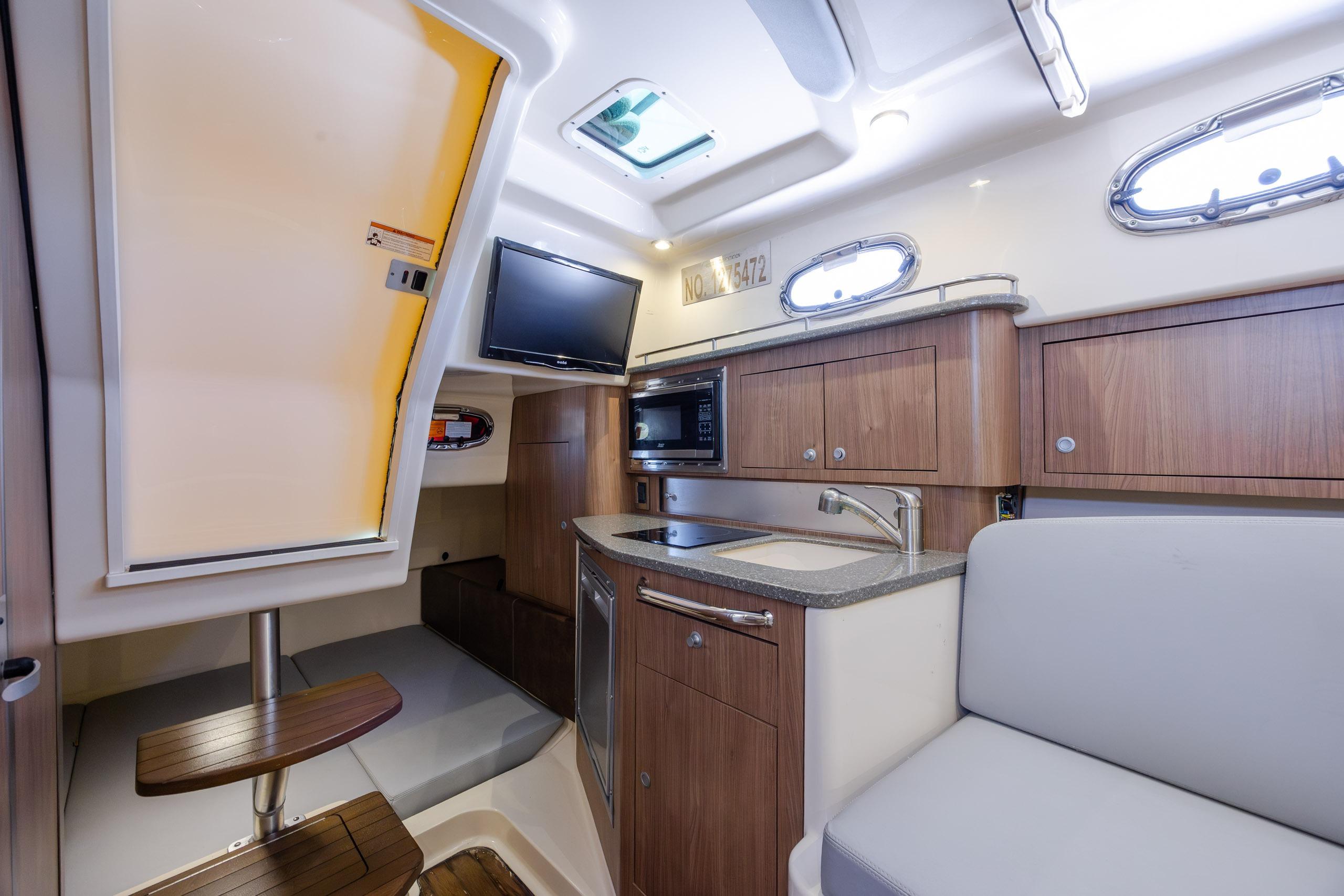 Interior of 2017 Boston Whaler 315 Conquest boat with kitchenette and seating area.