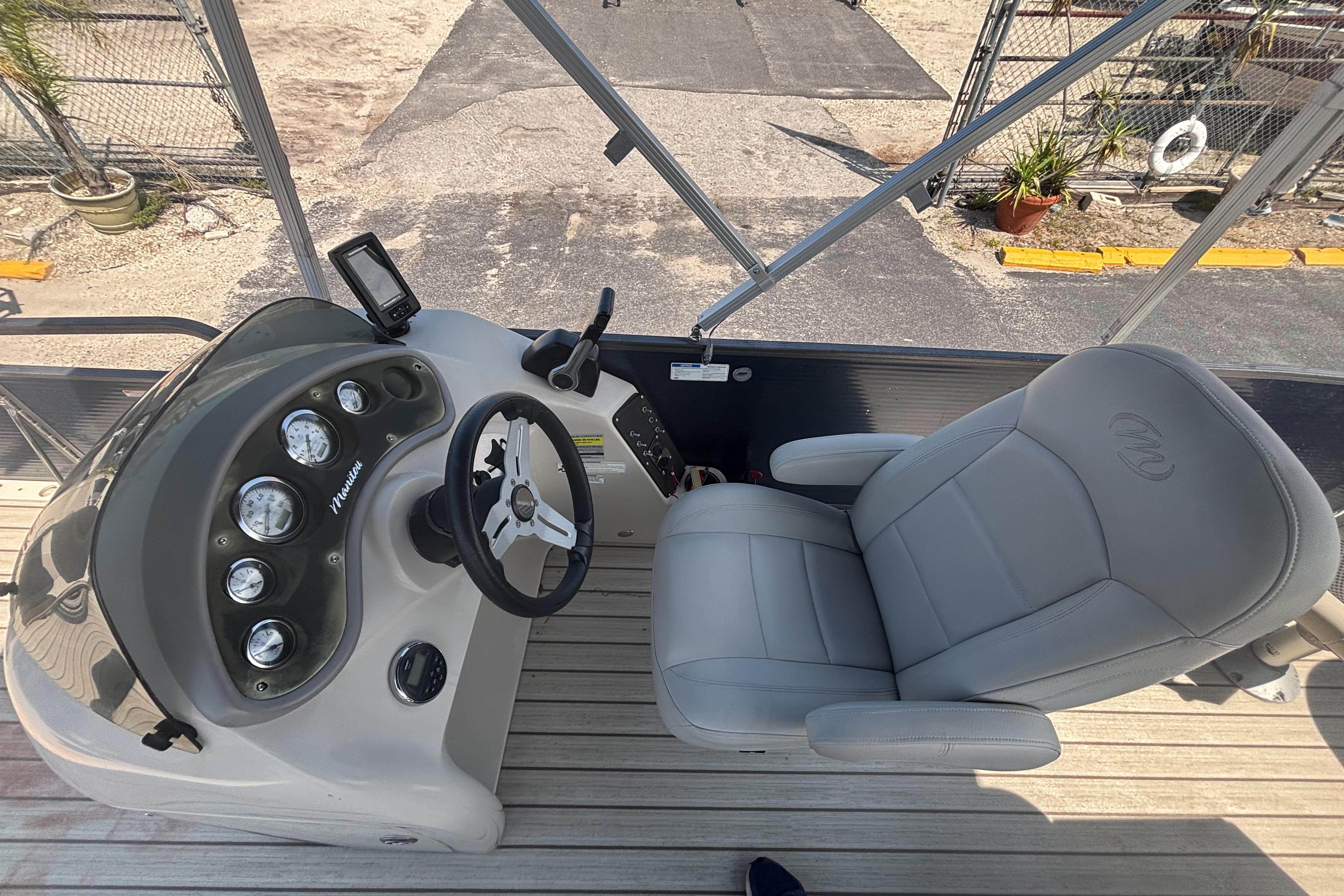 2015 Manitou 20 Oasis Angler boat interior with steering console and captain's chair.