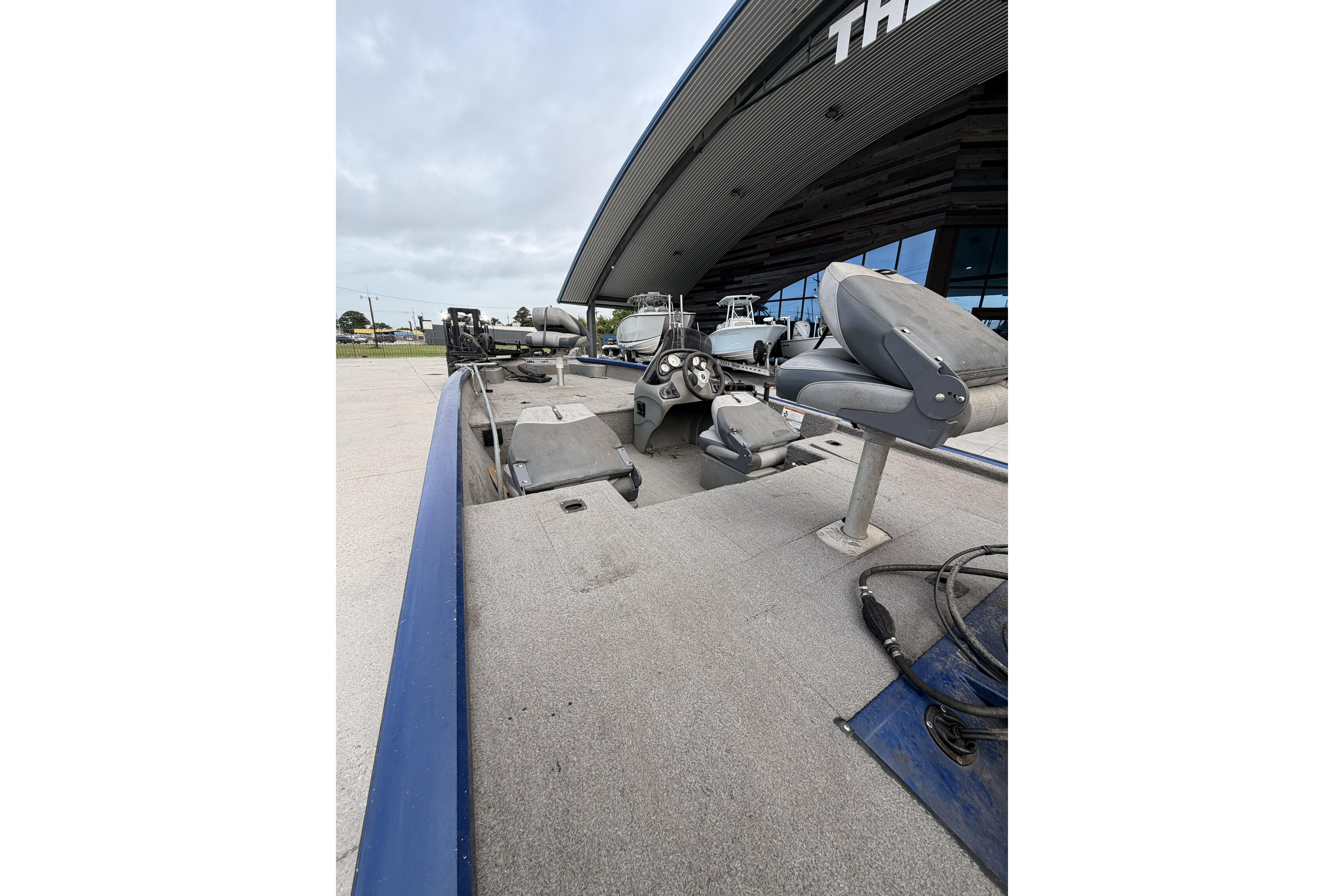 2012 Bass Tracker Pro 17 boat with gray interior, parked outdoors near a building.
