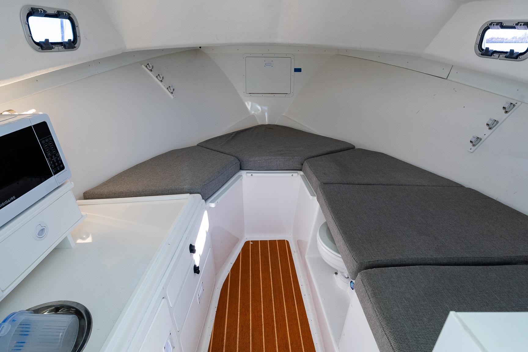 2024 Steiger Craft 31 Fisherman cabin interior with seating, microwave, and wood flooring.