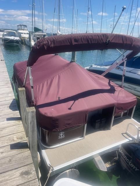 A 2018 Bennington 18SL pontoon boat docked, featuring a maroon canopy.