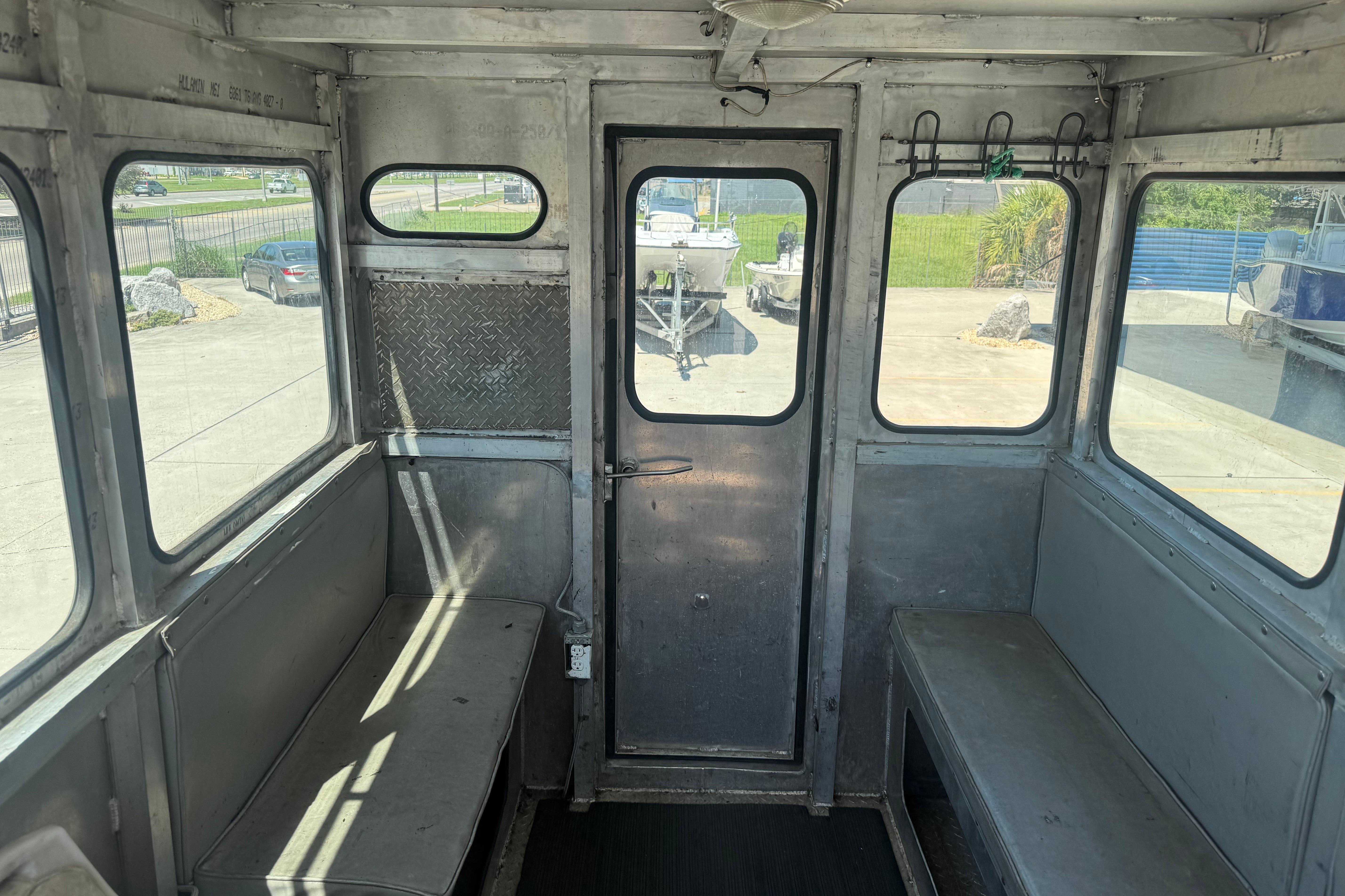 Interior of a 2010 Custom Aluminum Work Boat 33, featuring metal benches and windows.
