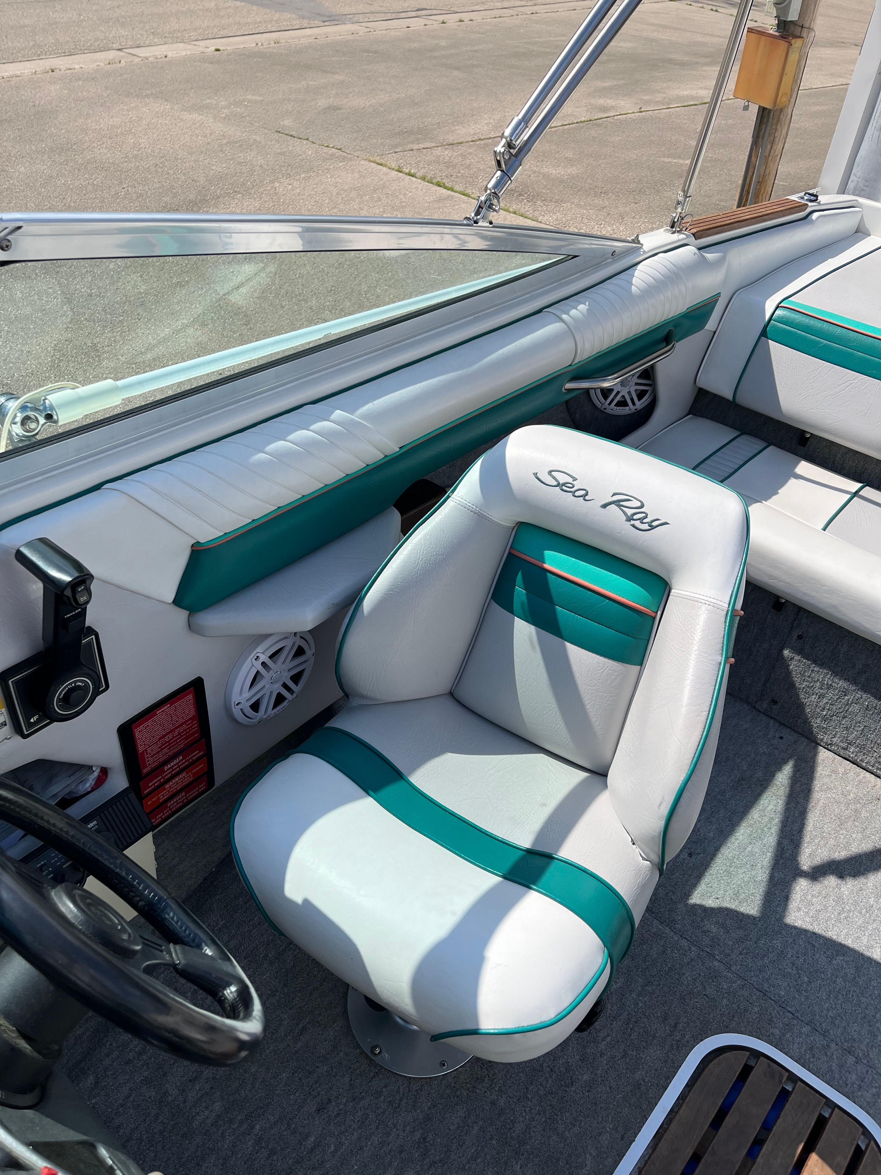 A 1992 Sea Ray 220 Bow Rider with teal and white seating and a steering wheel.