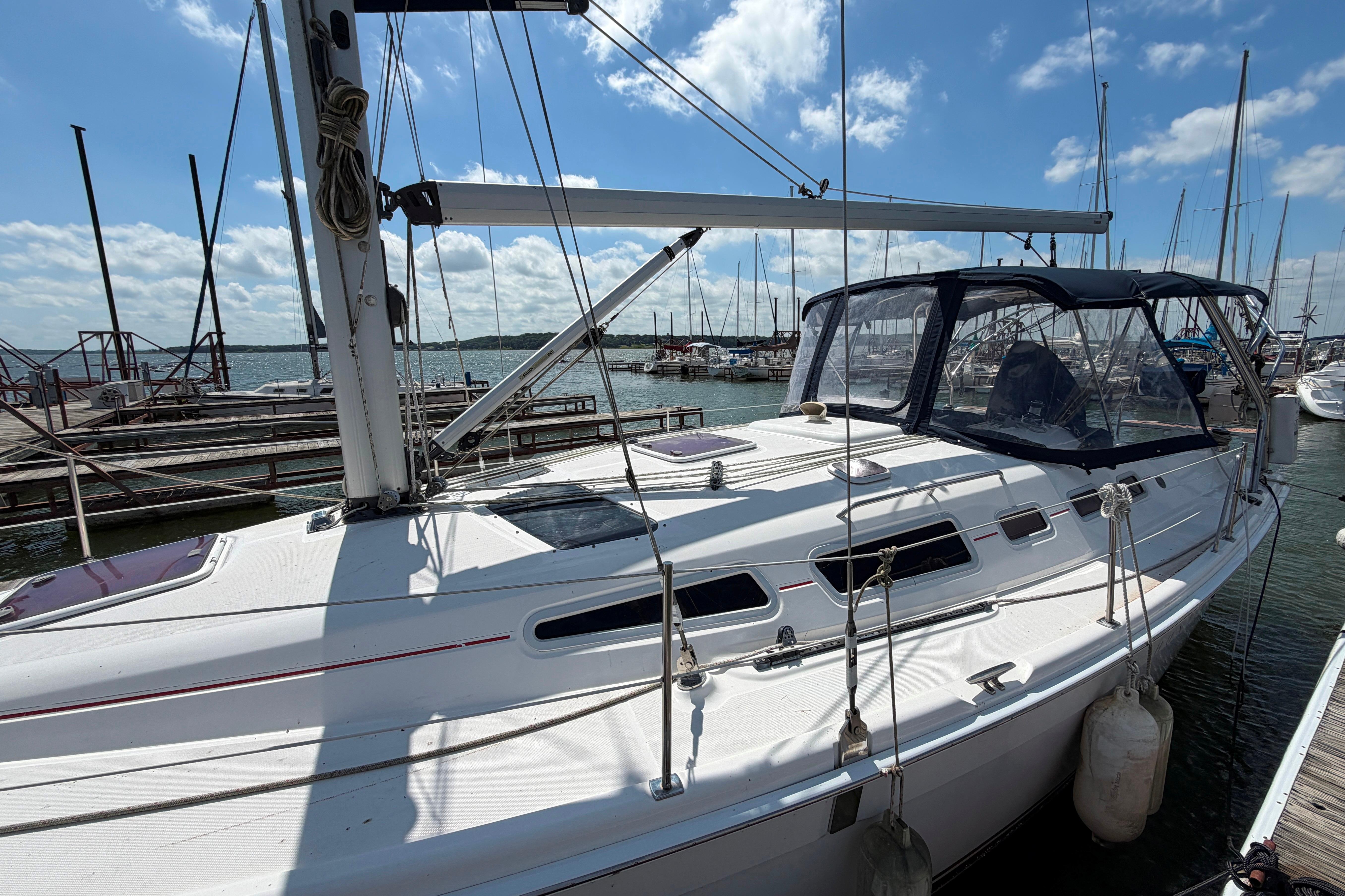 Sailboat docked at marina, 2005 Hunter 38 model, under clear blue sky.
