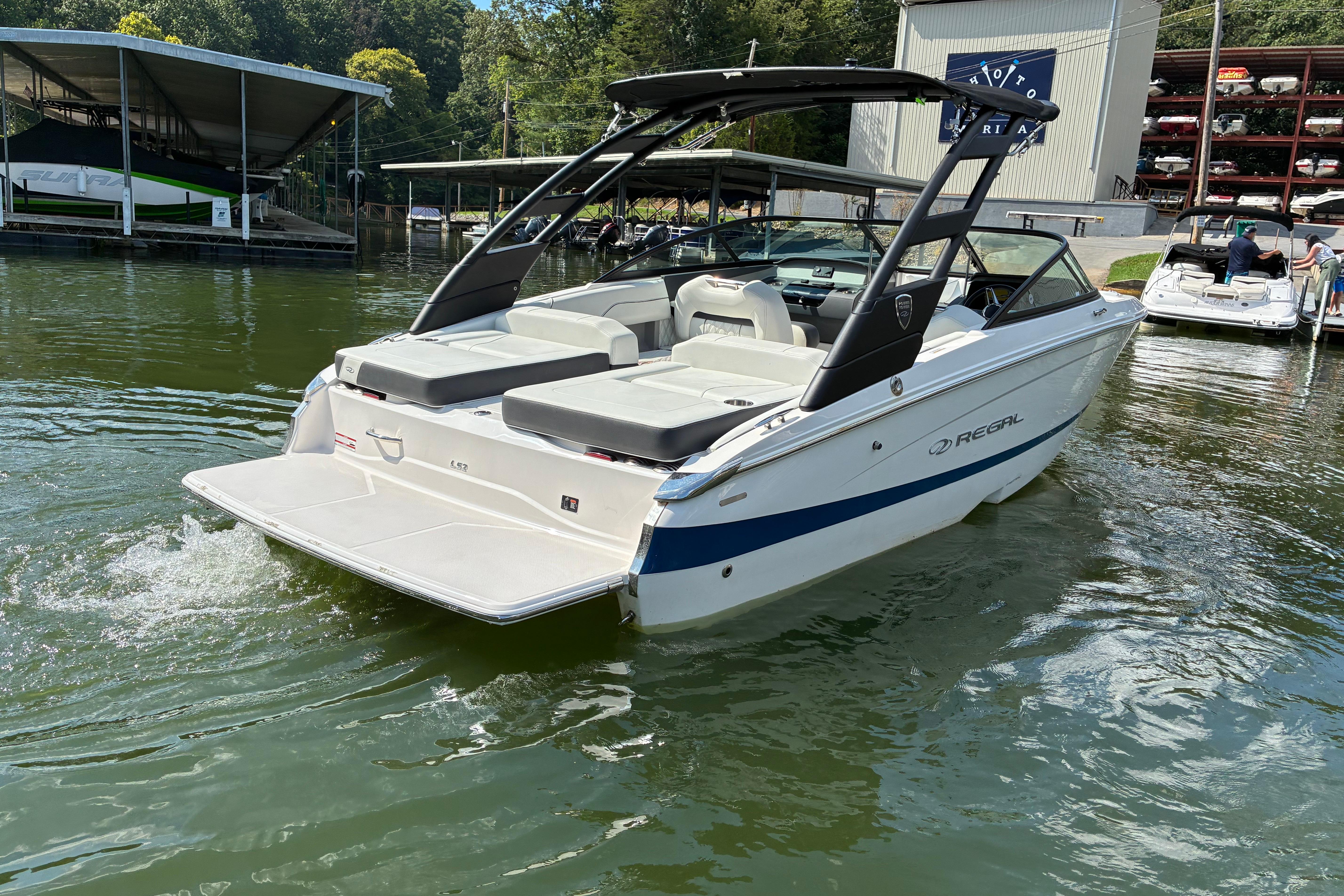 2025 Regal LS2 boat on water near marina, showcasing sleek design and spacious seating.