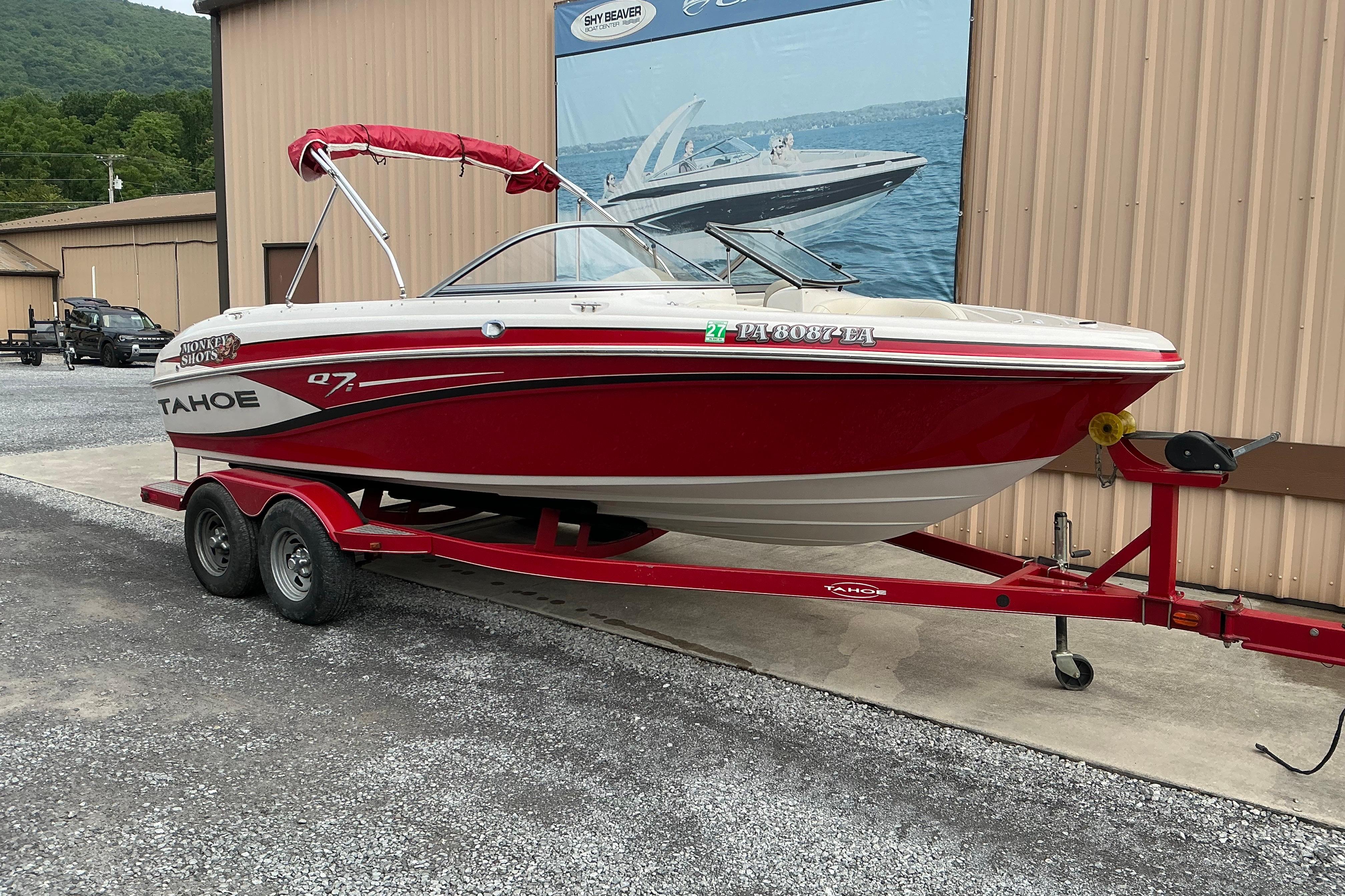 Red 2014 Tahoe Q7i boat on trailer, parked outside a building.
