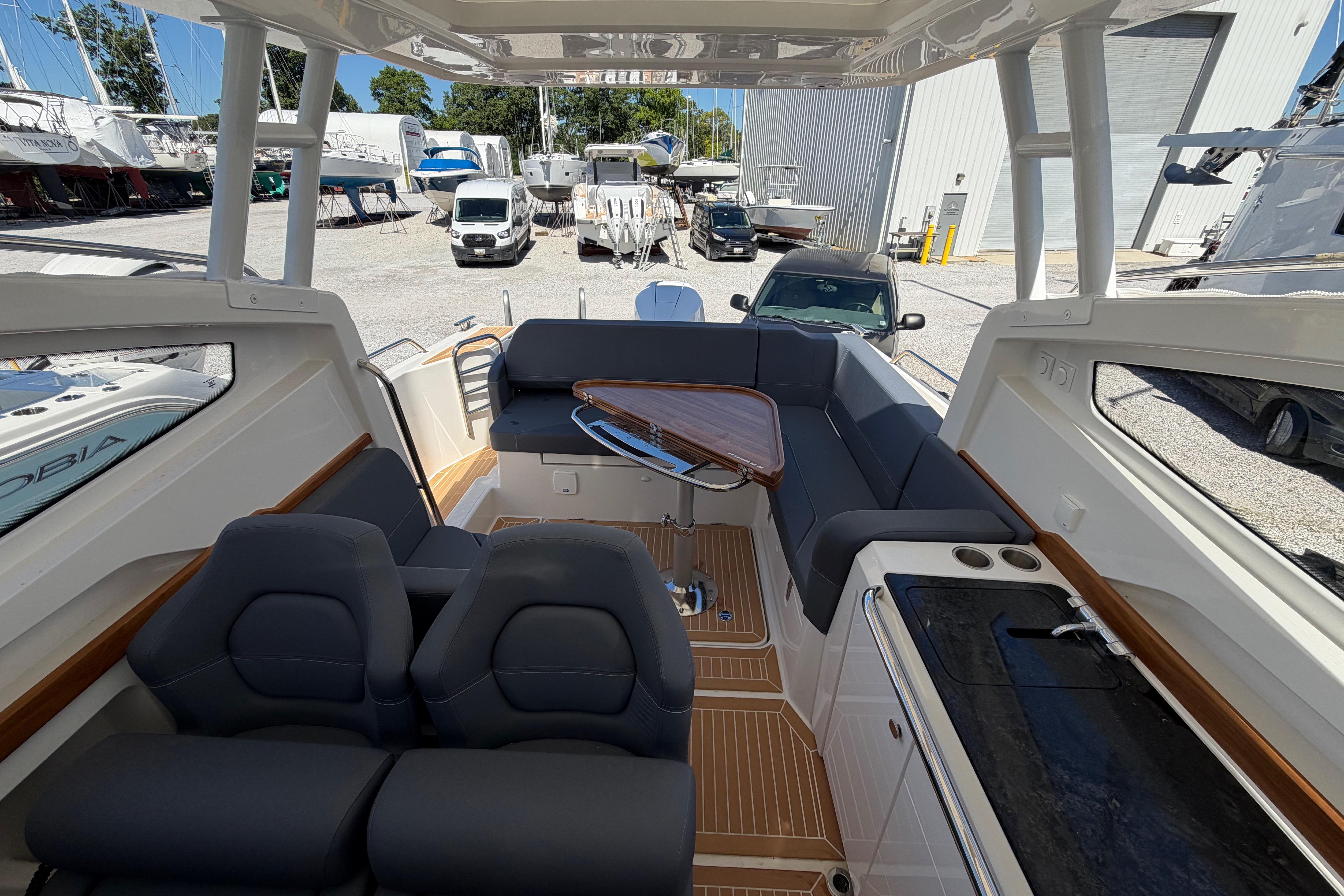 Interior of 2025 Nimbus Weekender 9 boat with seating and table, docked in a marina.