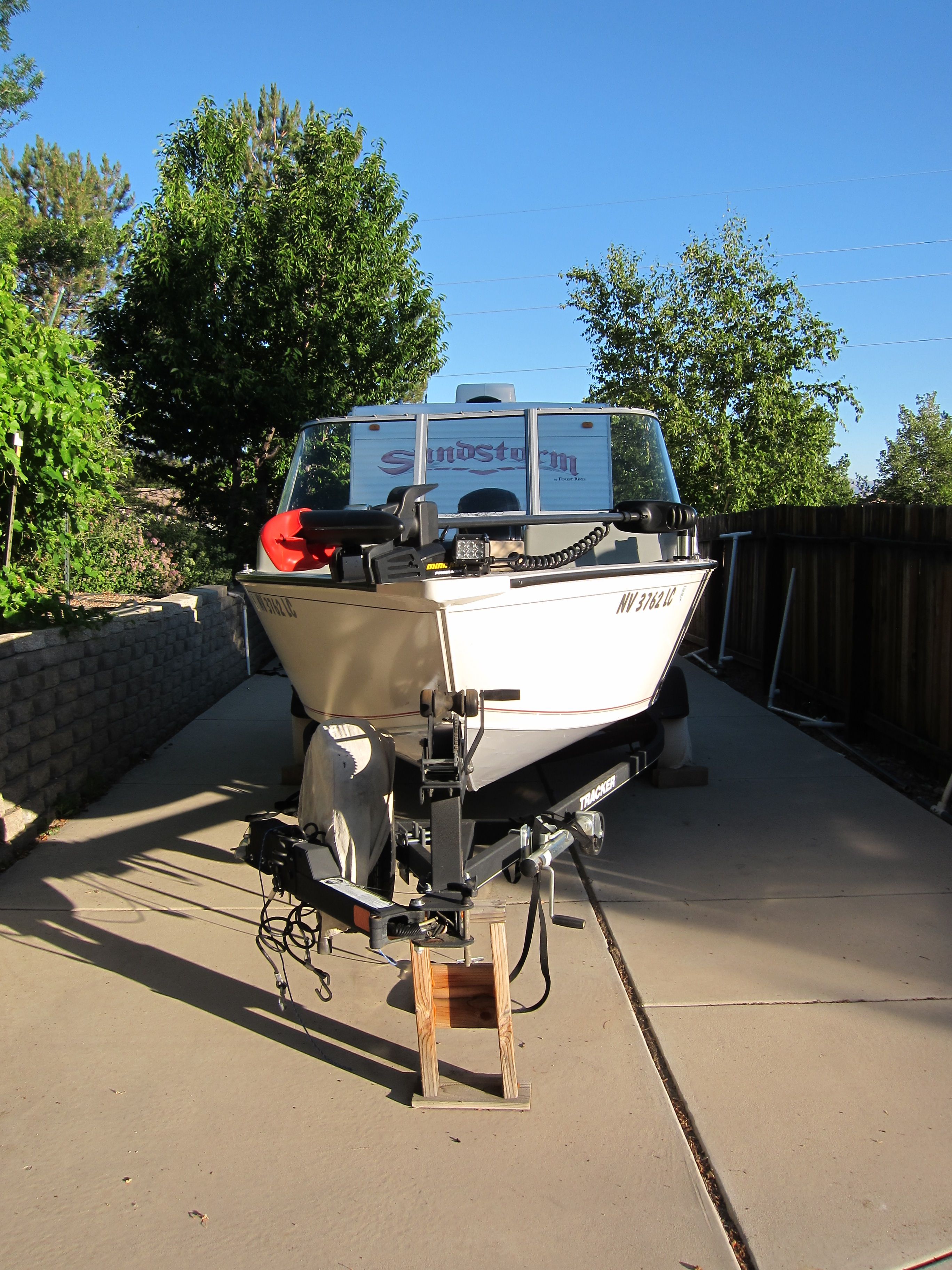 A 2018 Tracker Pro Guide V-16 WT on a trailer, surrounded by trees and a fence.