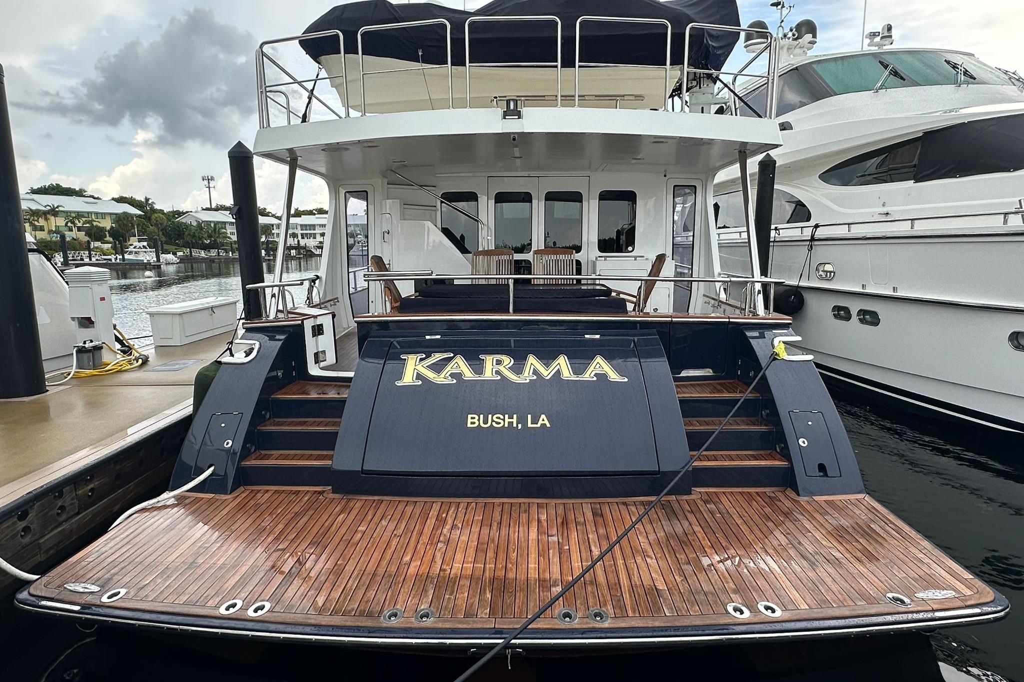 2023 Marlow Explorer 66E-CB yacht docked, featuring "Karma" nameplate, wooden deck, and elegant design.