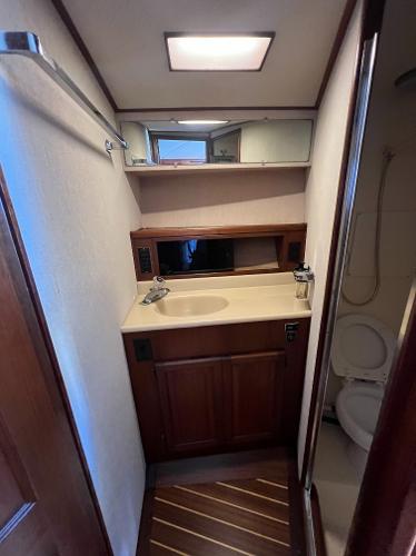 A boat bathroom with a sink, mirror, and toilet.