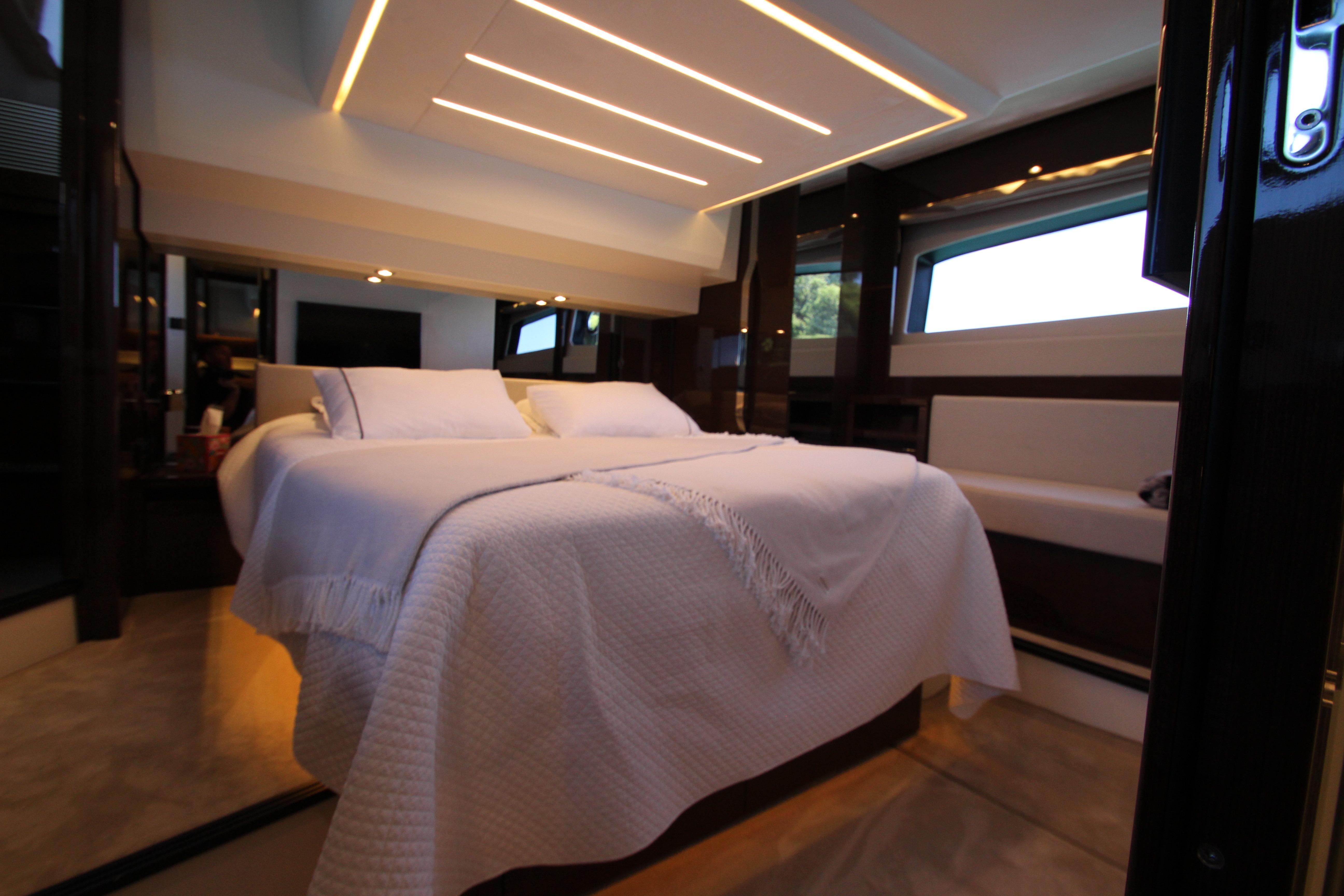 Luxurious bedroom interior of 2022 Prestige 520 yacht with modern lighting and elegant bedding.