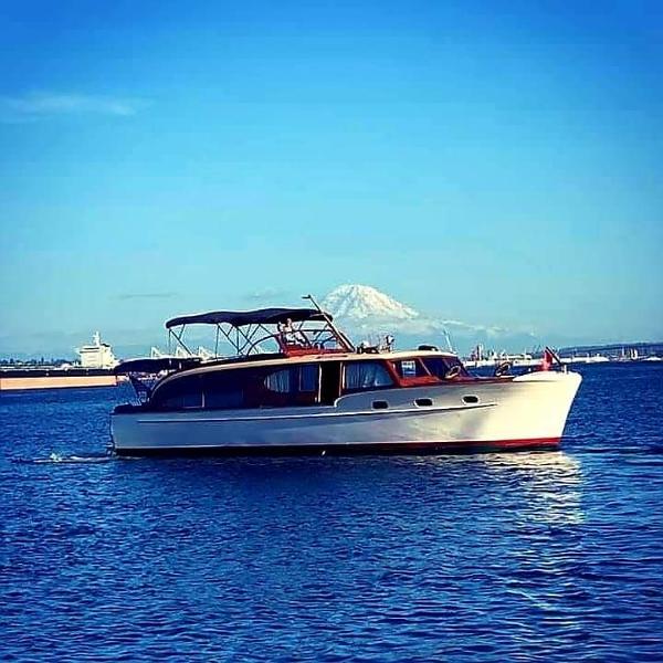1951 Chris-Craft Catalina boat on blue water with mountain backdrop.