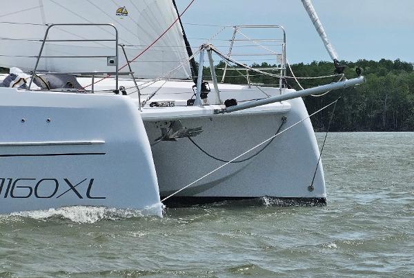 2025 Seawind 1160 XL catamaran sailing on calm waters near a forested shoreline.