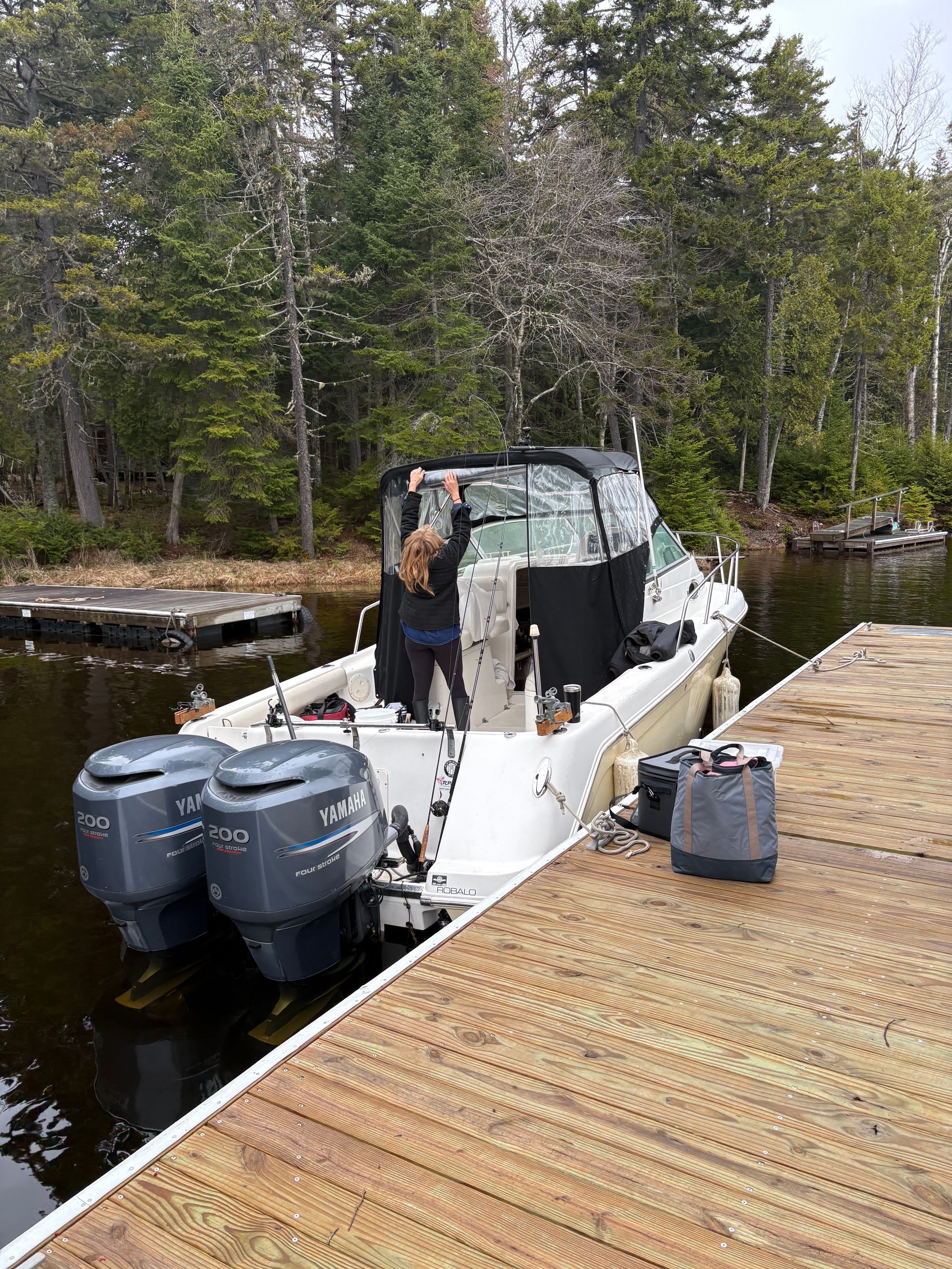 A person secures a cover on a Robalo R265 Walkaround boat at the dock.