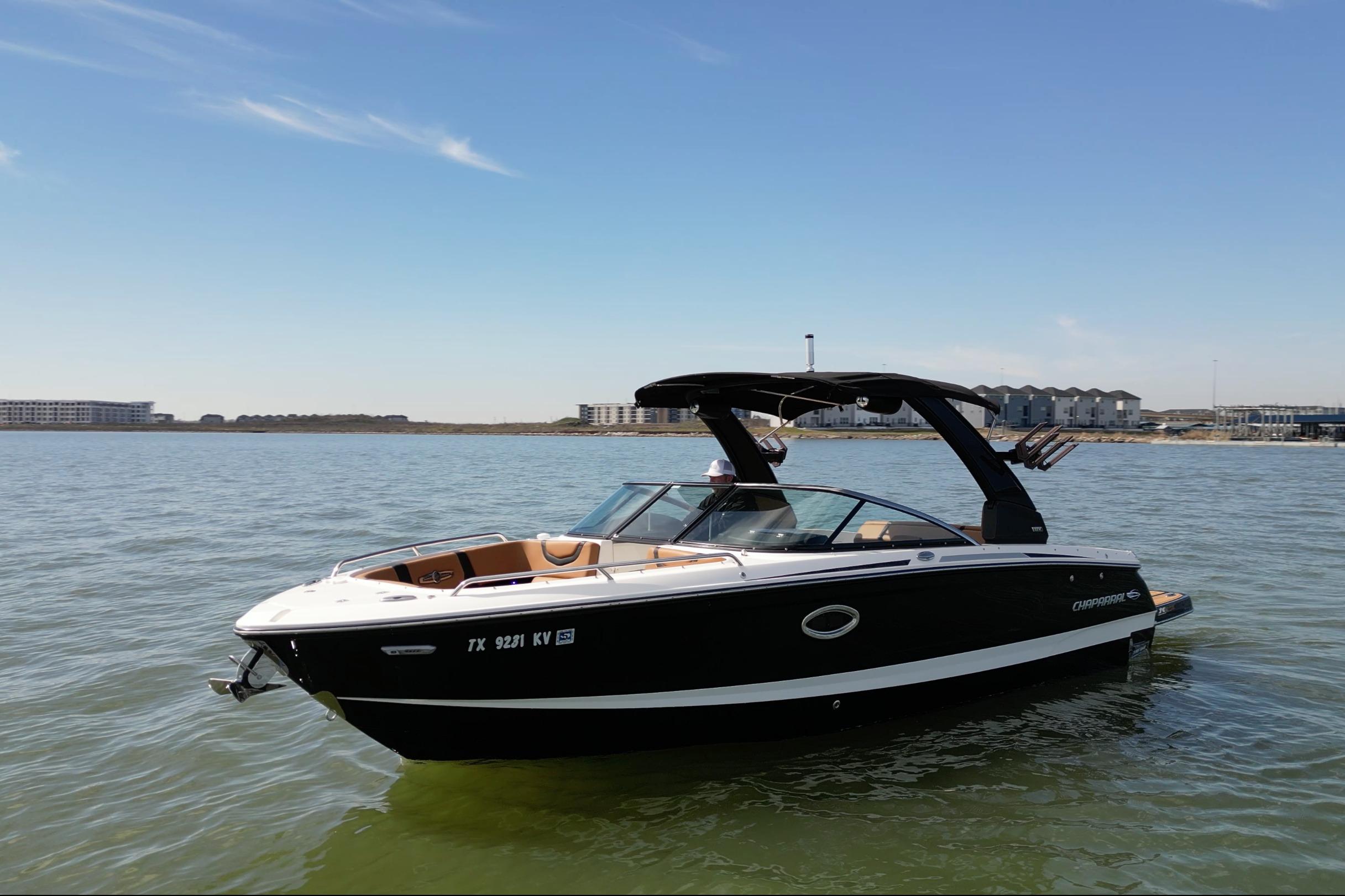 2023 Chaparral 26 Surf boat on calm water under clear blue sky.