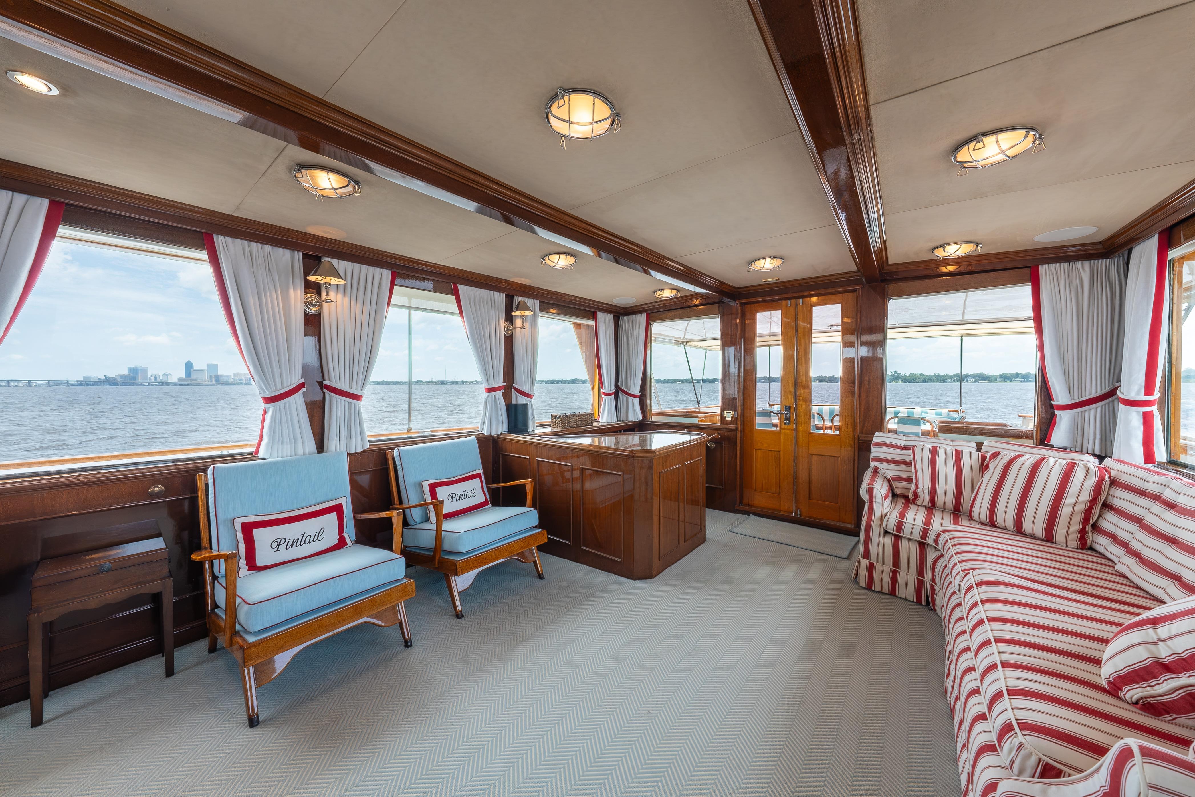 Interior of a 1963 Trumpy Classic yacht with elegant wood and striped furnishings.