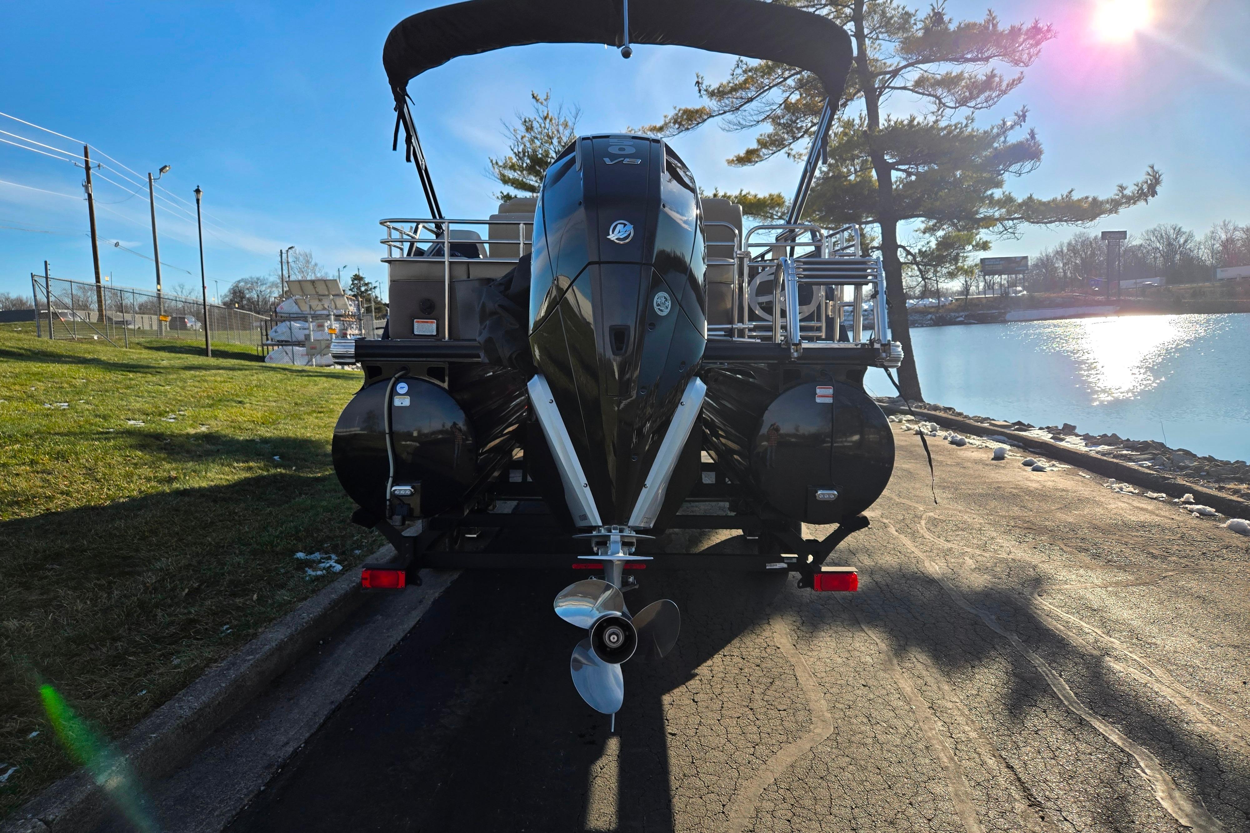 2024 Regency 250 LE3 Sport boat parked by a serene lakeside under a clear blue sky.