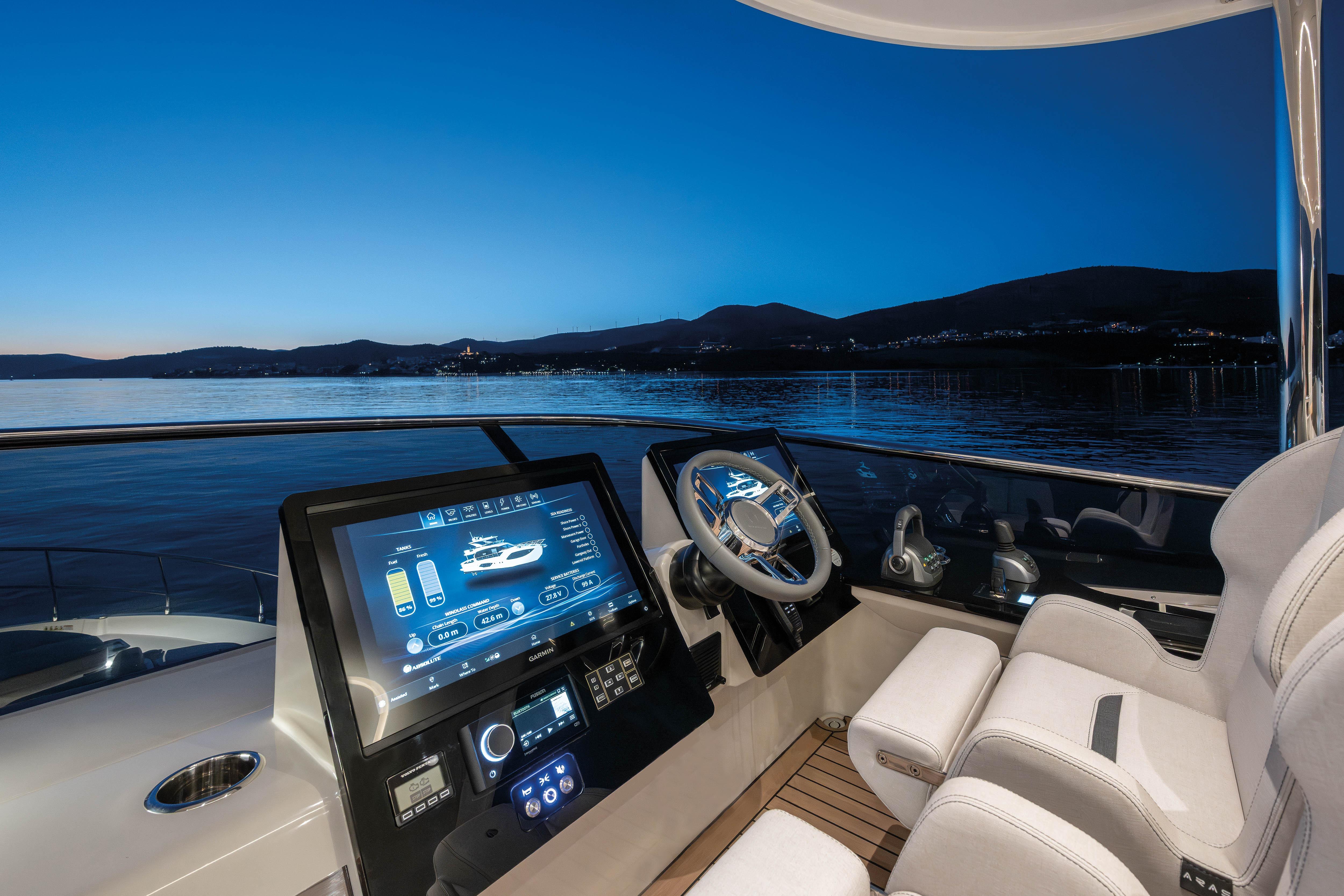 The cockpit of a modern yacht with digital display and controls at sunset.