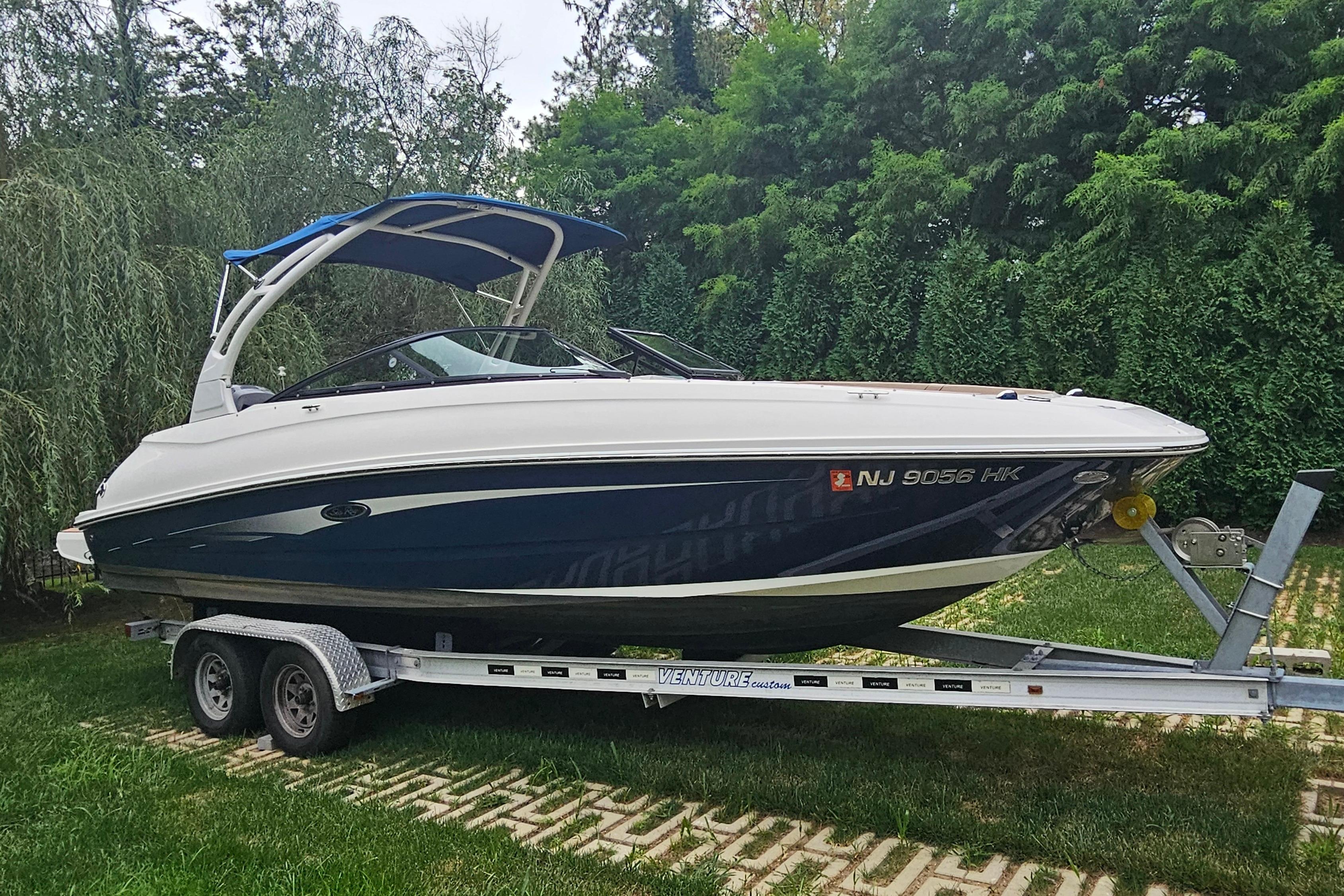 2017 Sea Ray SDX 240 Outboard boat on trailer, surrounded by lush greenery.